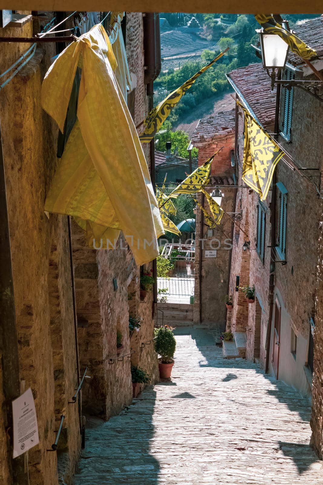 View of a characteristic street in the town of San Casciano dei Bagni. Note the beautiful medieval flags. by silentstock639