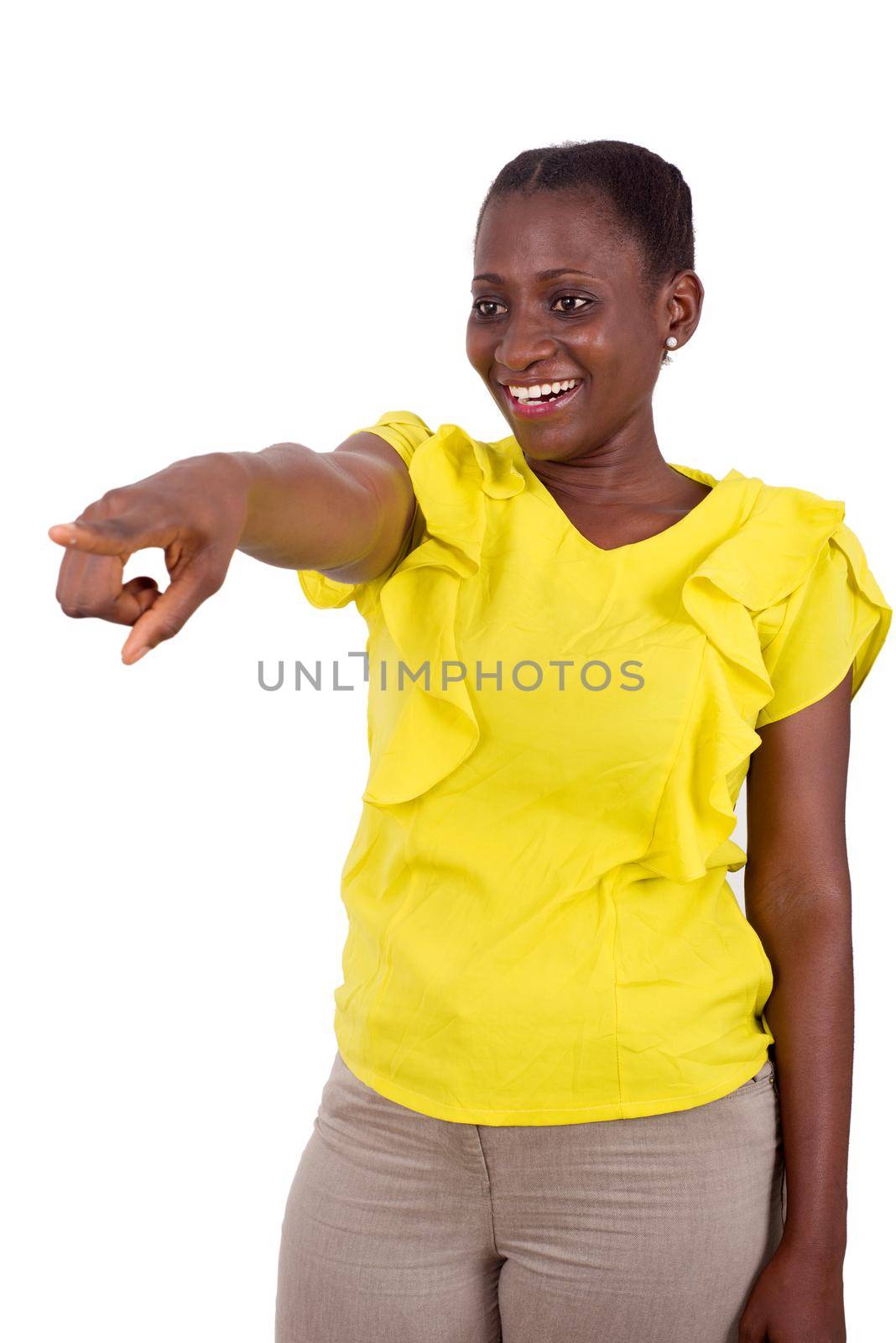 young girl standing in yellow camisole on gray background shows something with laughing finger.