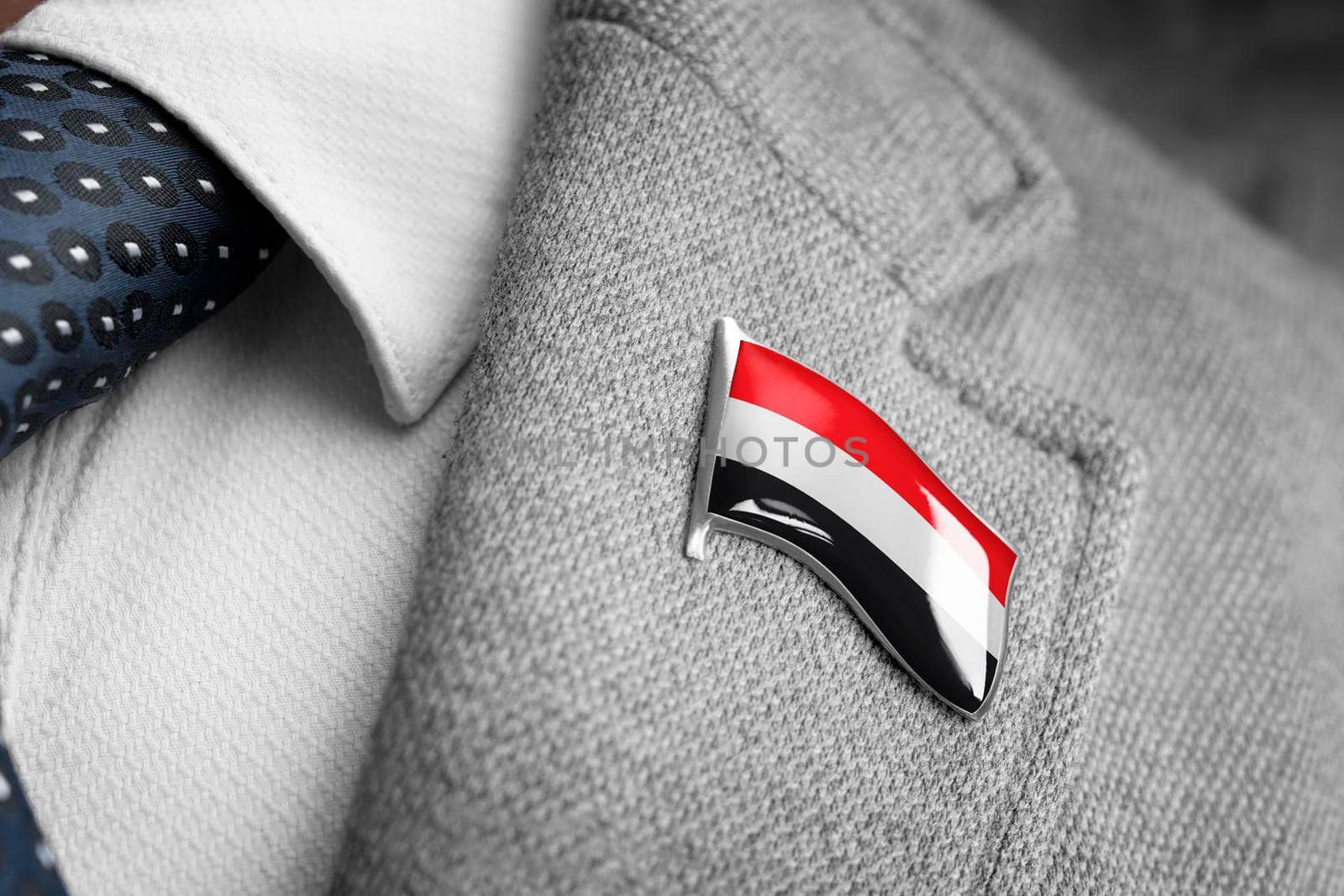 Metal badge with the flag of Yemen on a suit lapel.