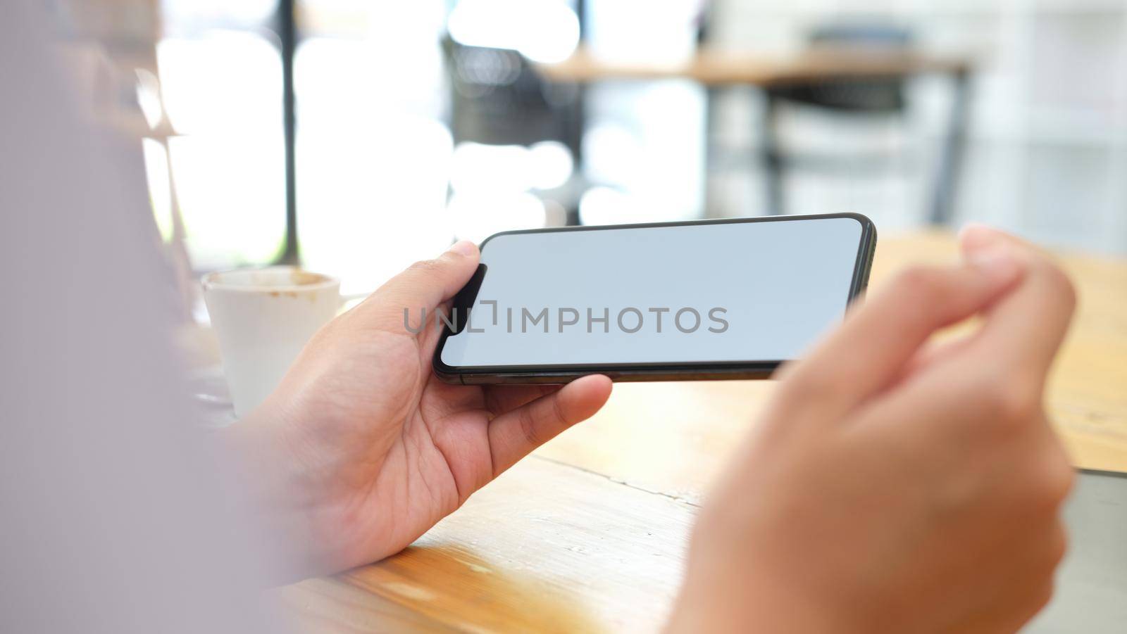 Close up of man hand holding smart phone. Blank screen mockup for graphics display montage.