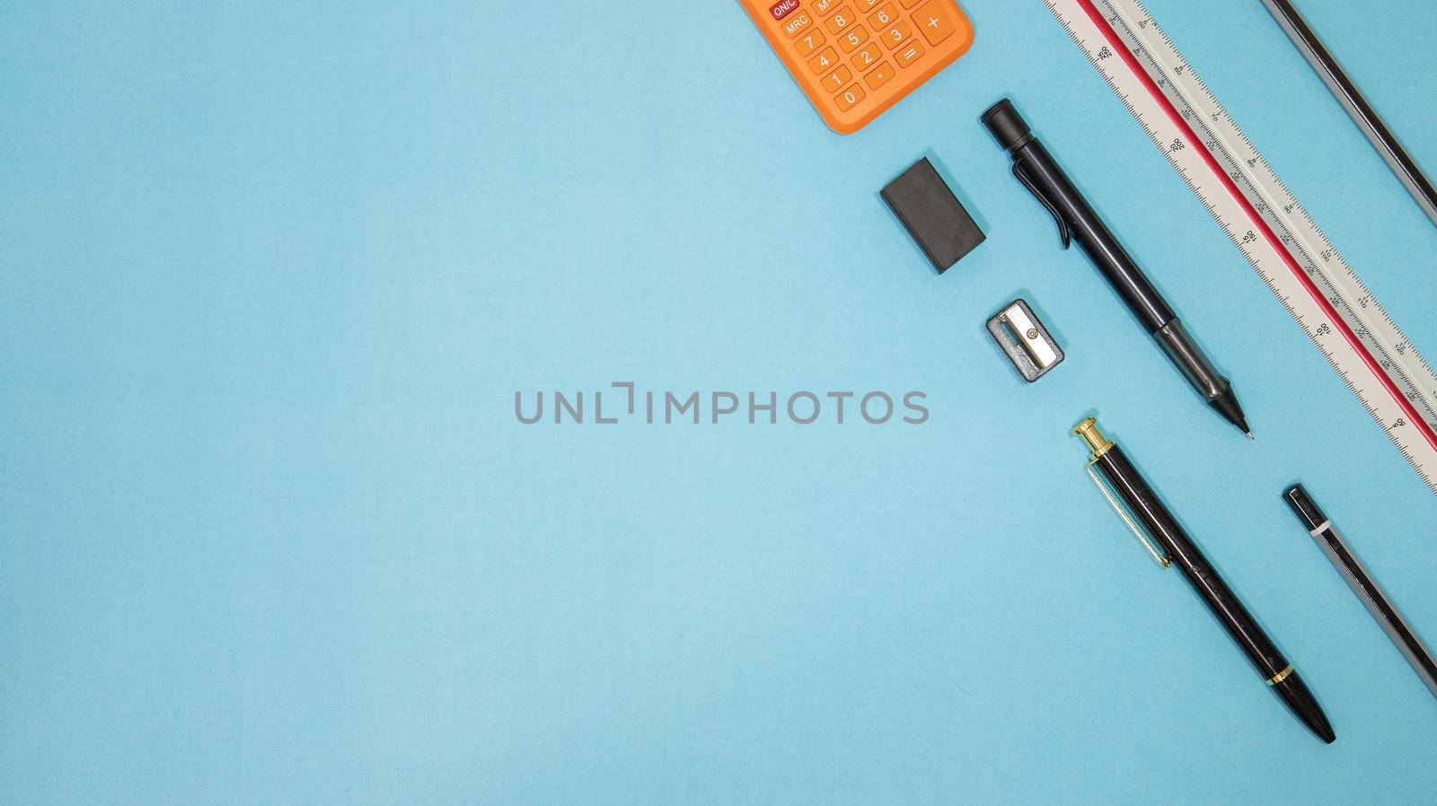 Education or back to school Concept. Top view of Colorful school supplies with books, color pencils, calculator, pen cutter clips and apple on blue pastel background. Flat lay