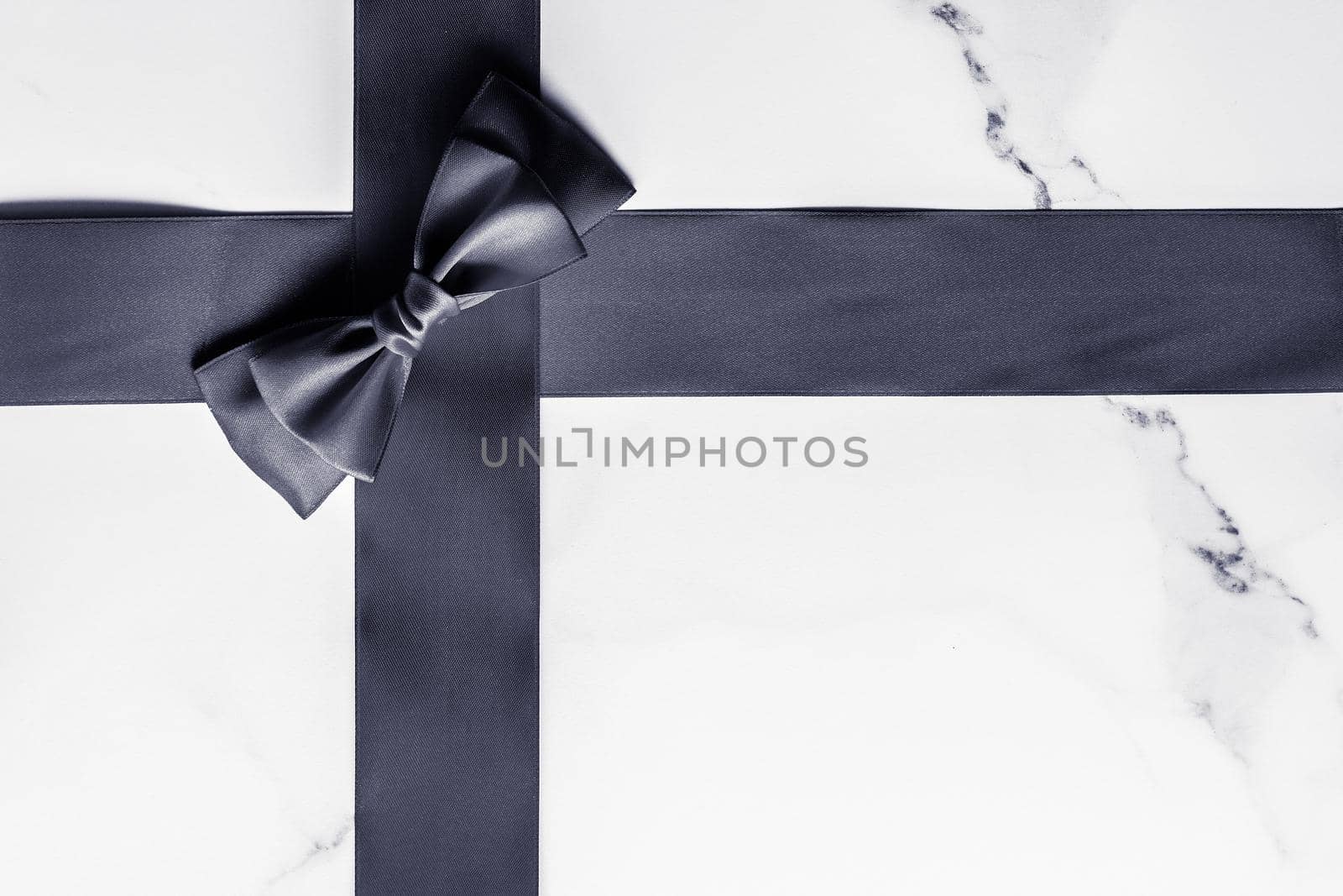 Holiday gift, decoration and sale promotion concept - Black silk ribbon and bow on marble background, flatlay