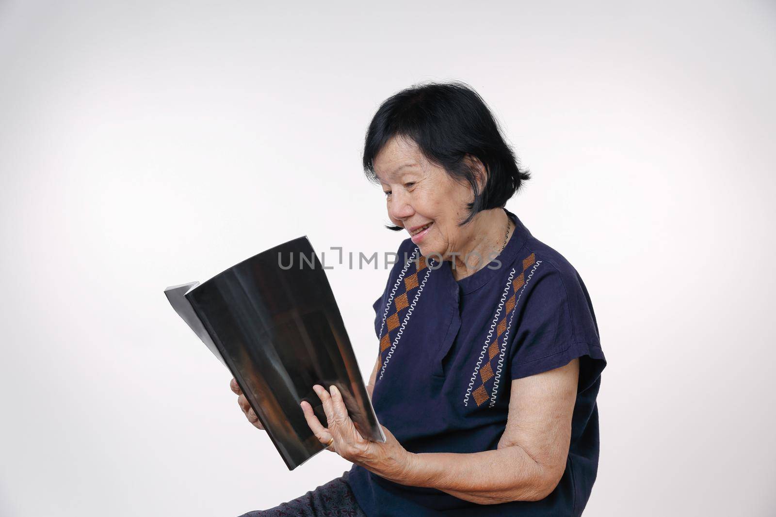 elderly woman reading a magazine on white background