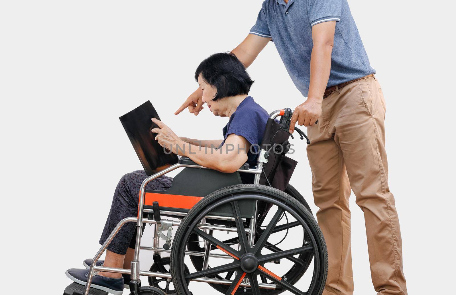 elderly woman reading a book on wheelchair with her son take care.