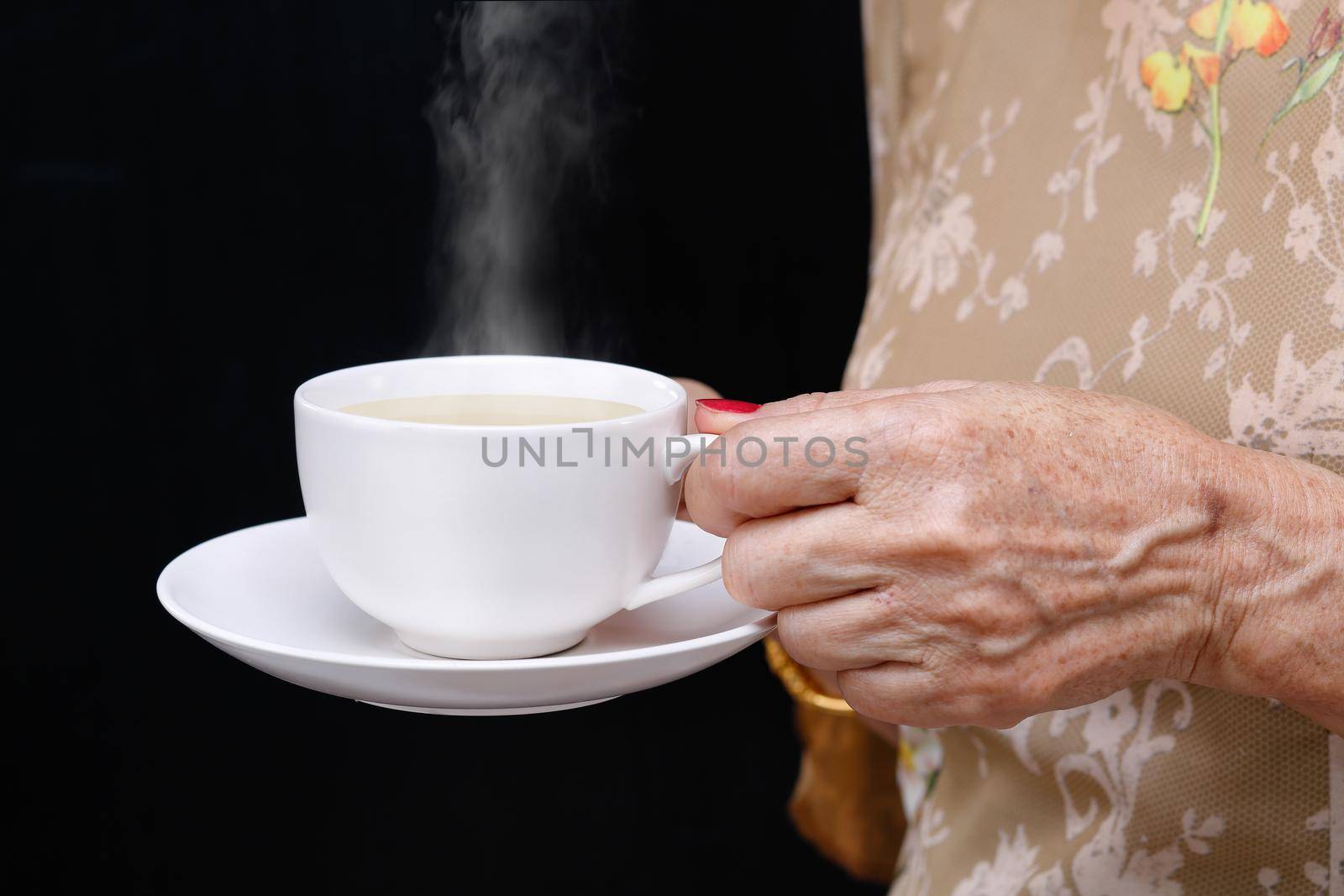 Senior woman holding a coffee cup .