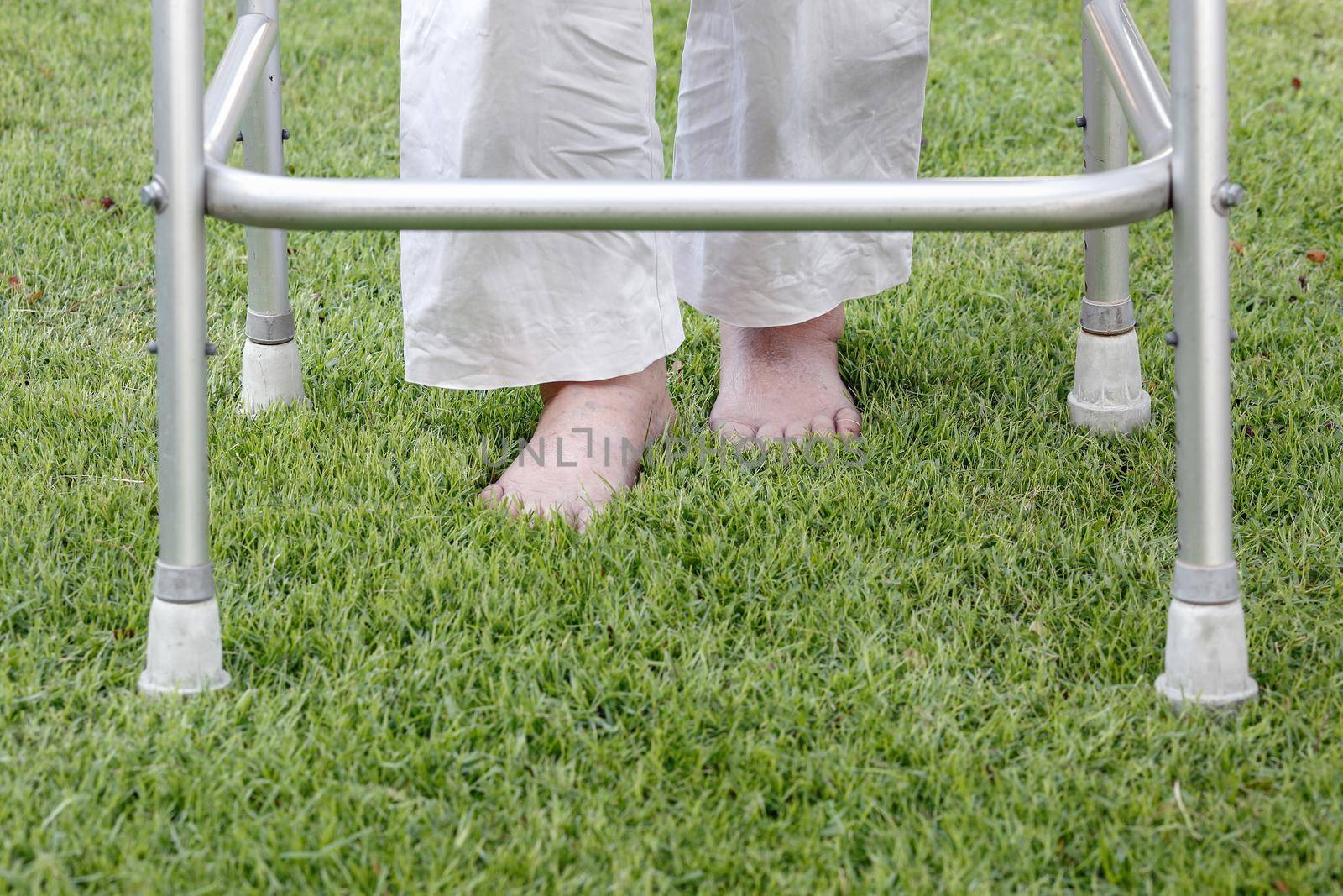Elderly woman walking barefoot therapy on grass in backyard. by toa55