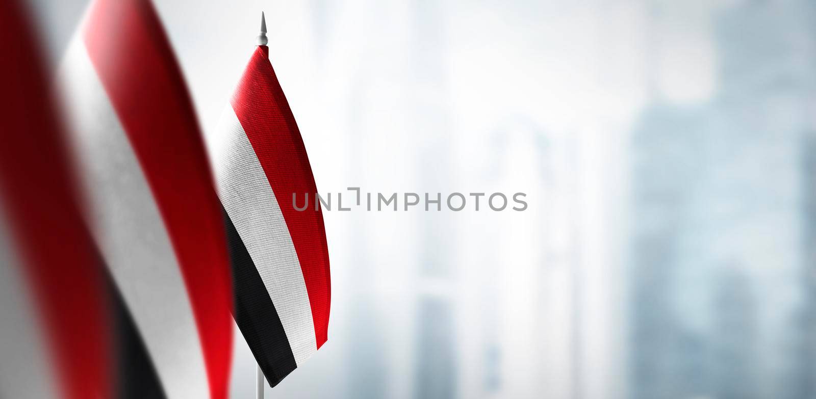 Small flags of Yemen on a blurry background of the city.