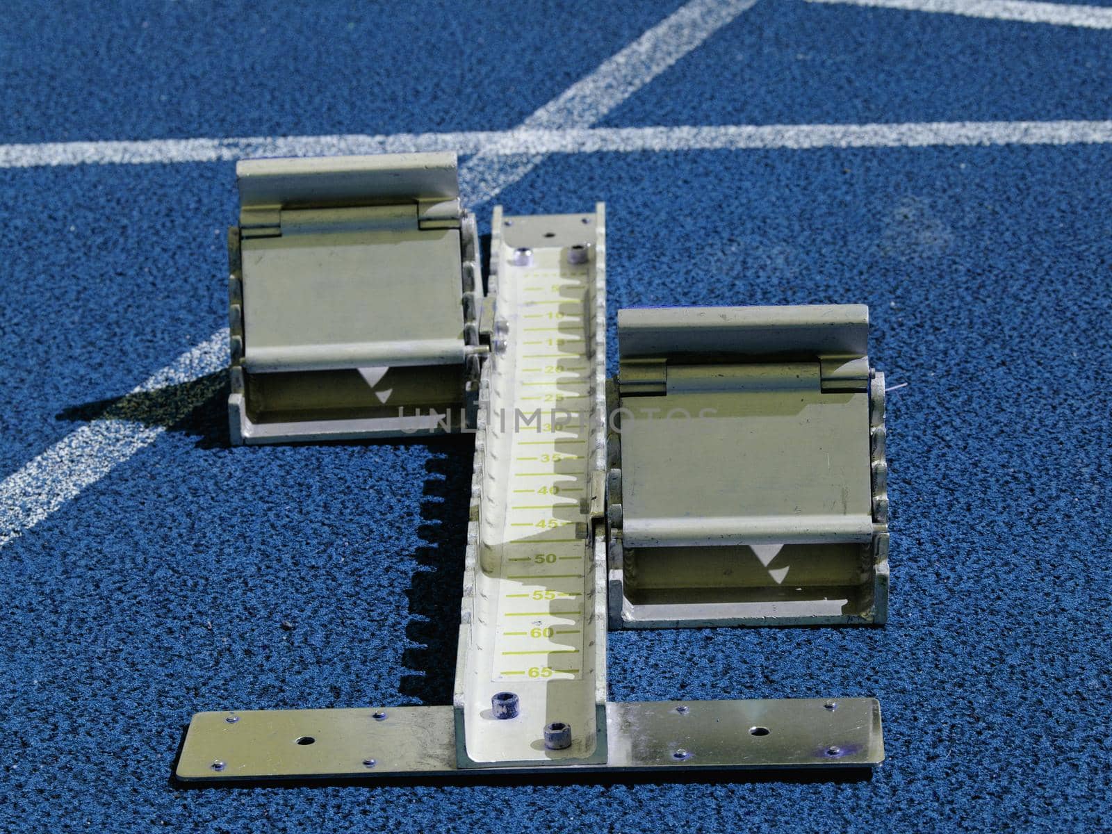 Set of starting block ready for sprint start on athletic stadium. Blue color filter