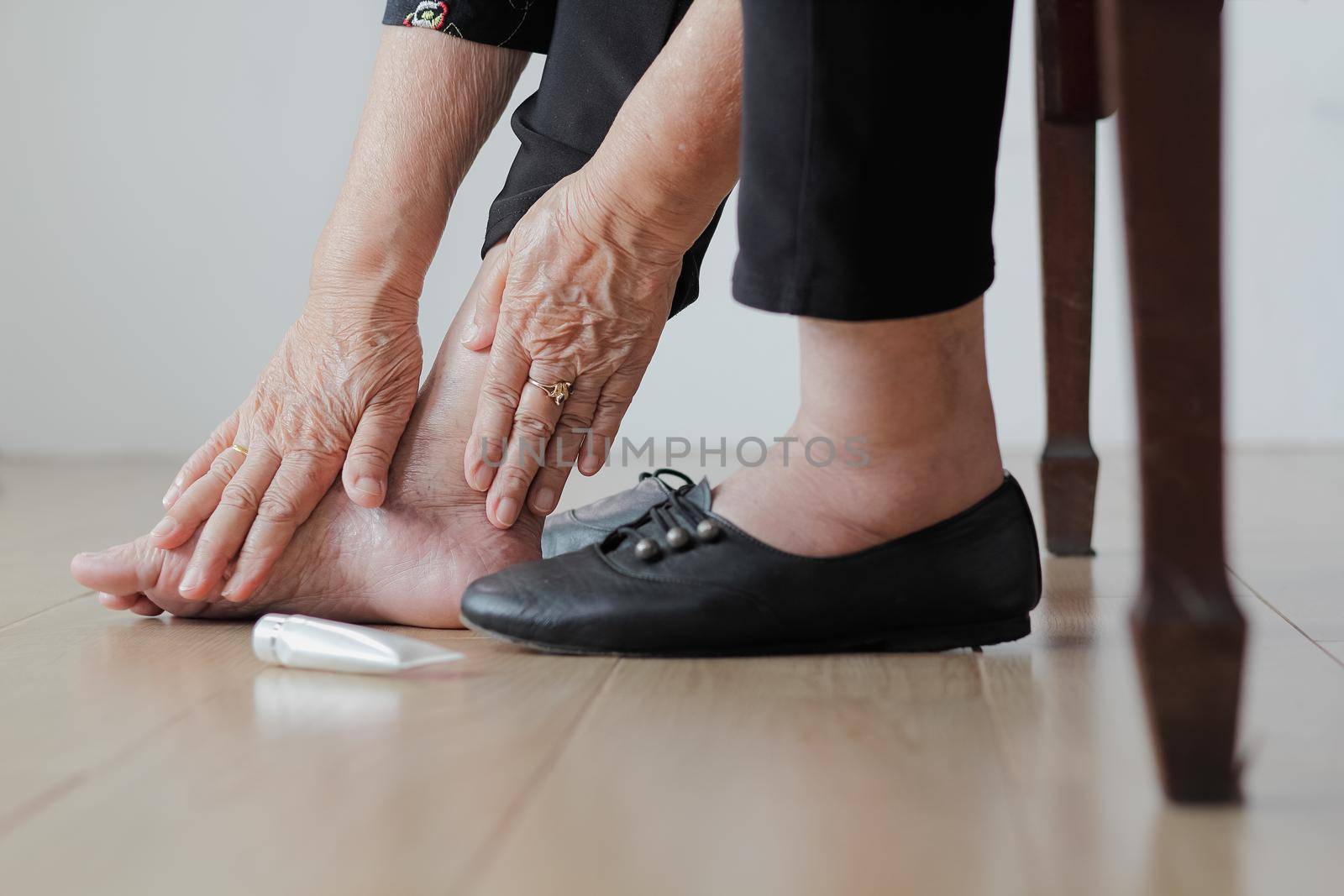 Elderly woman putting cream on swollen feet before put on shoes by toa55