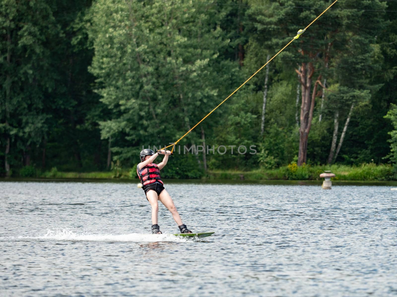 Straz, Czechia. 29th of July, 2021. Wake boarding  boy on lake, the forest in blurry background.
