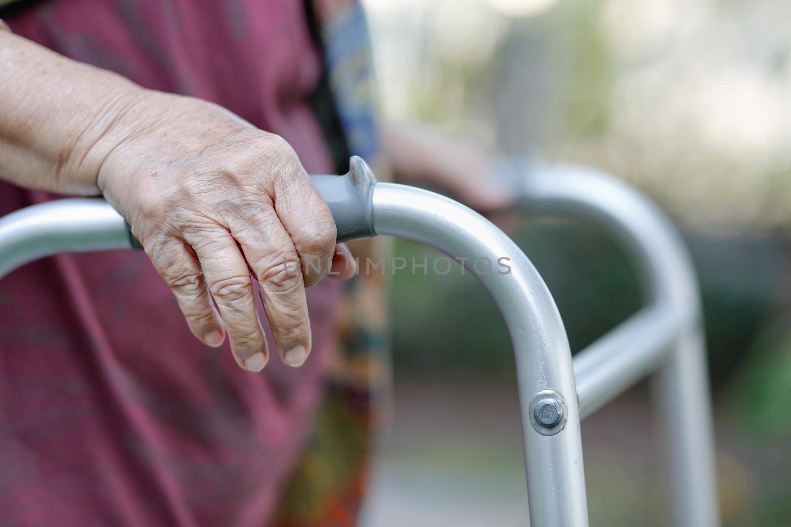 Elderly woman using a walker in backyard by toa55