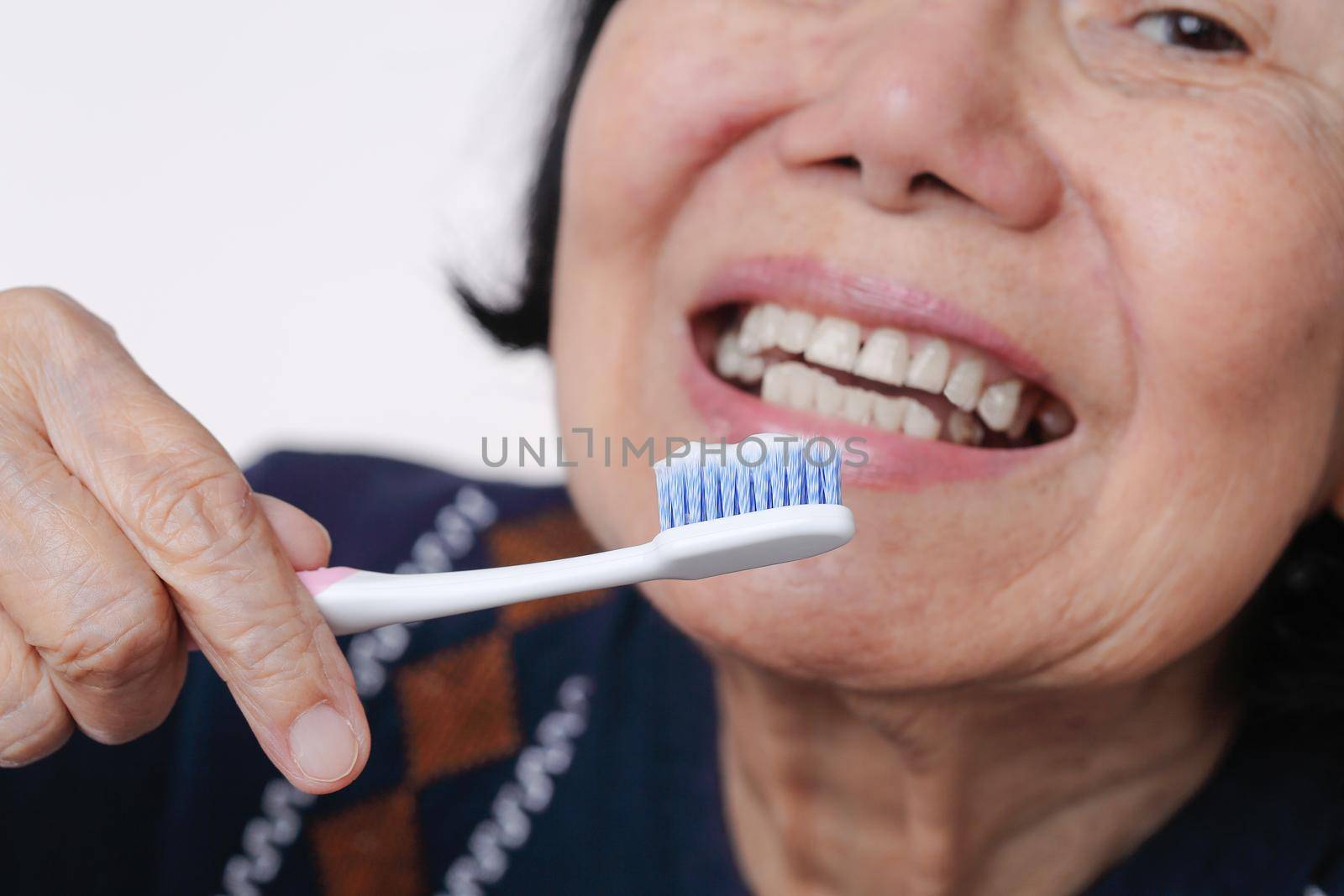 Asian elderly woman trying use toothbrush ,hand tremor . Dental health by toa55