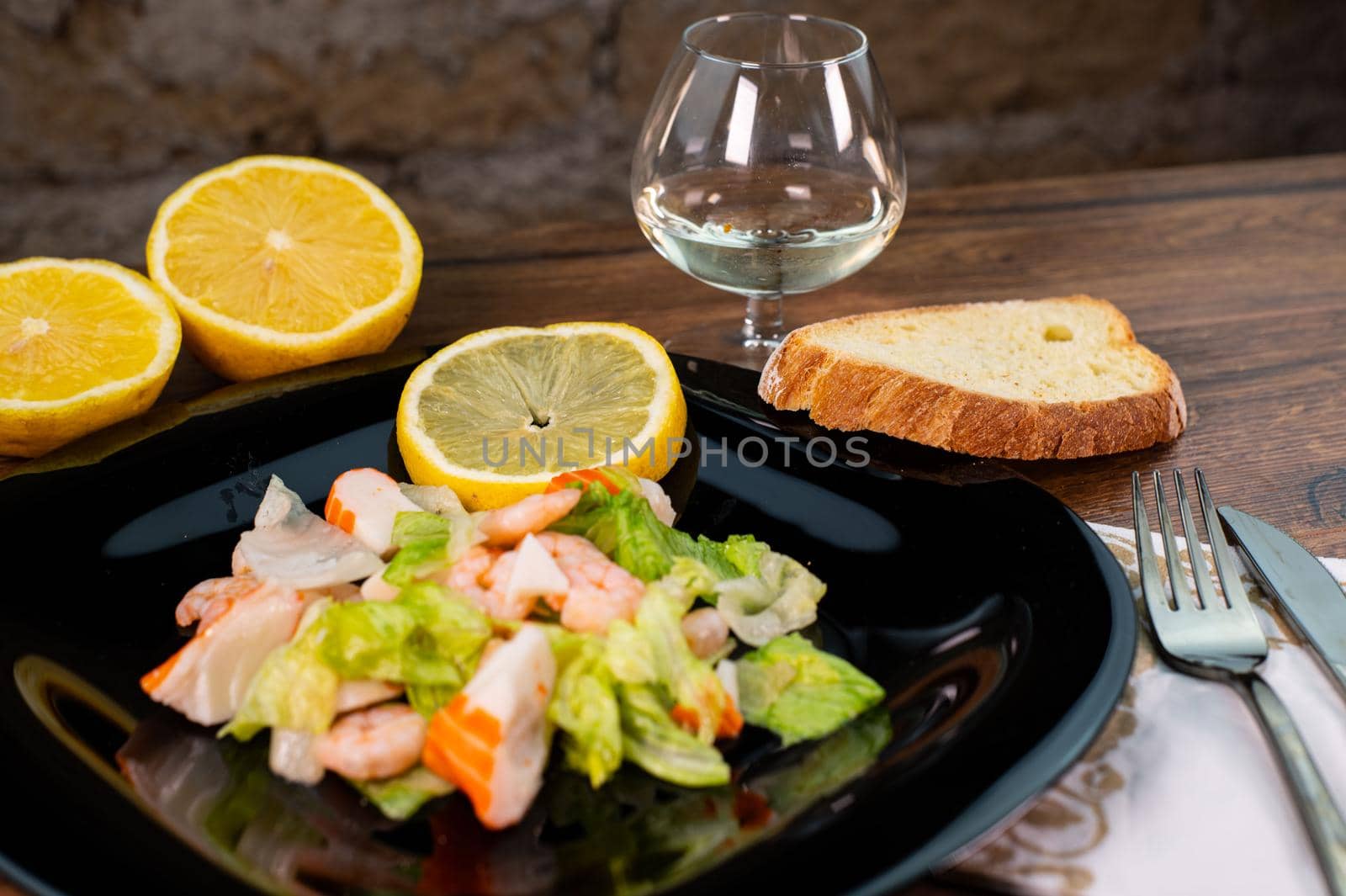 composition of a black plate with shrimp and surimi salad on wooden background