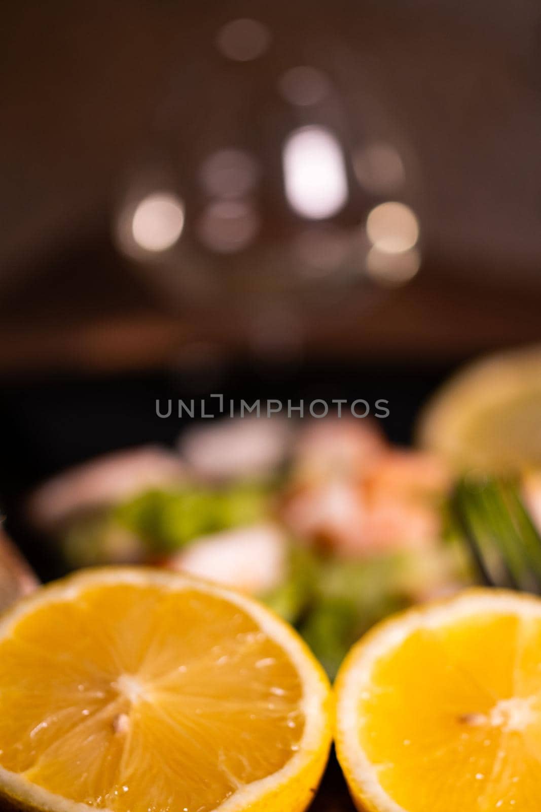 a lemon split in half in front of a plate of fish with a glass of white wine