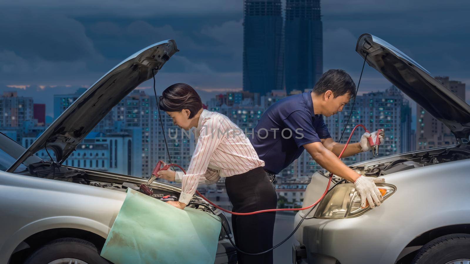 jump-start a car battery using cables on street in downtown