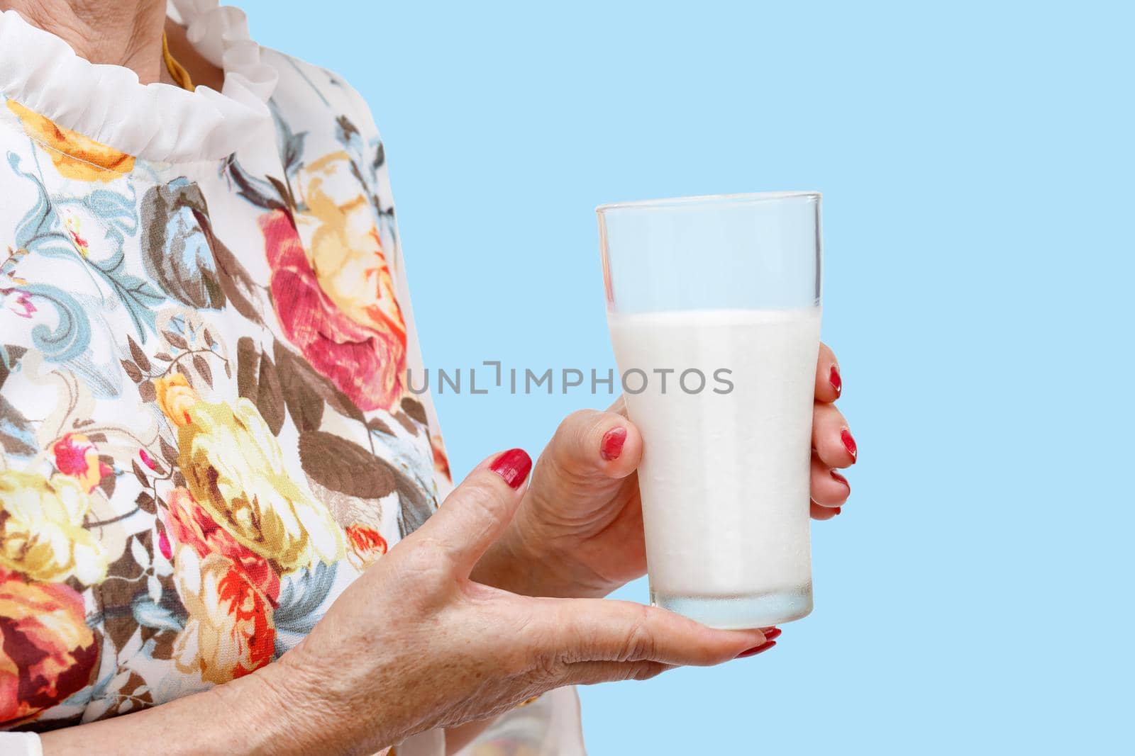 Senior woman holding a glass of milk  on blue background.