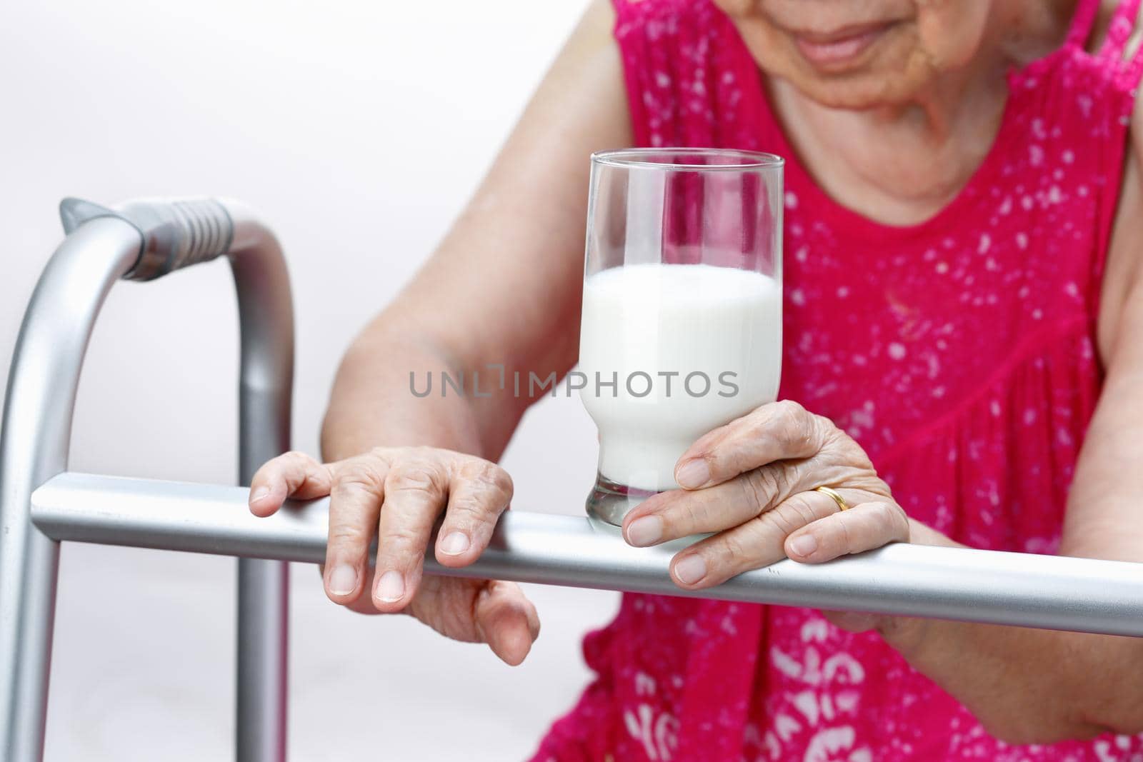 Grandmother holding a glass of milk , isolated over white background.