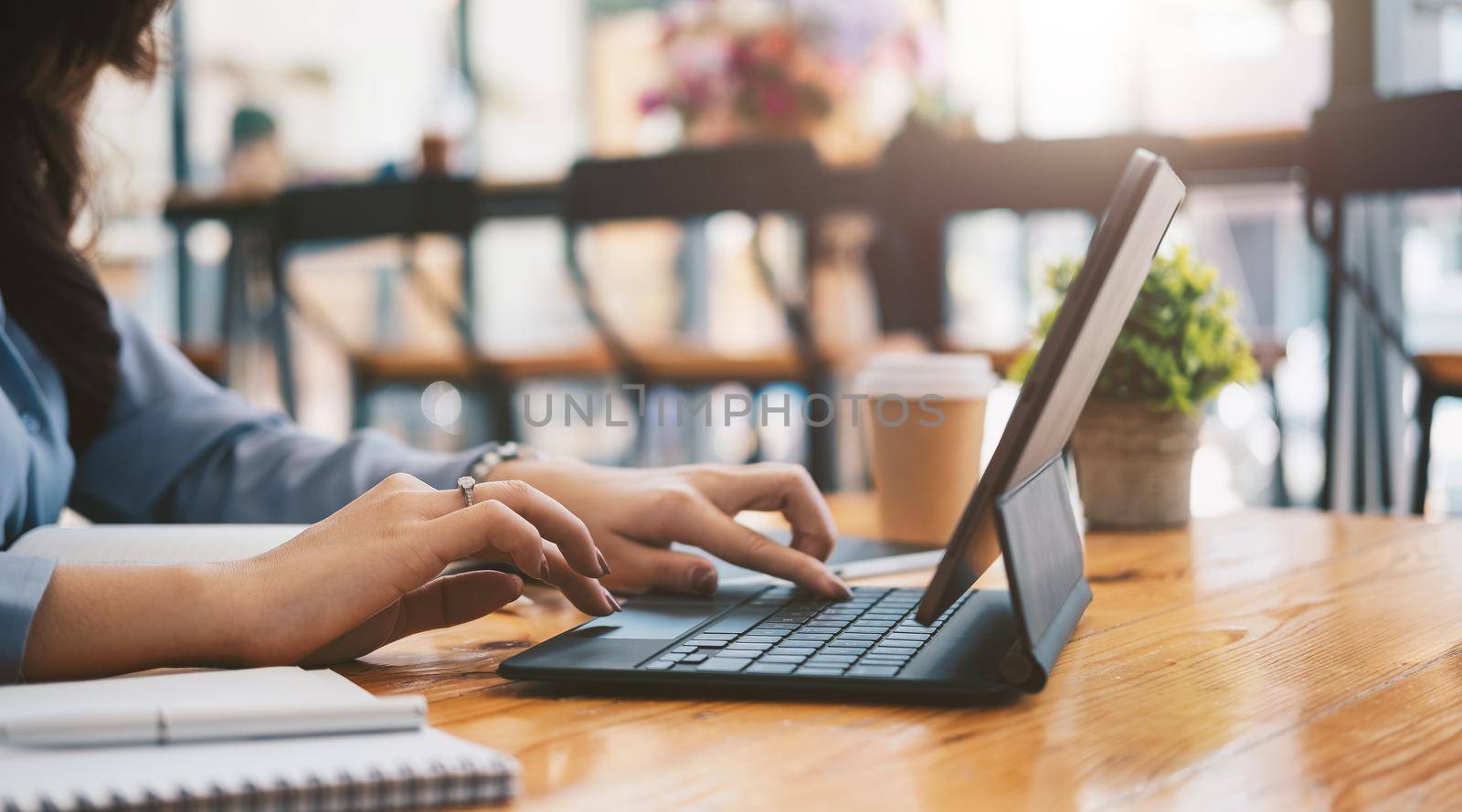 Close up of student girl hands comparing notes on digital tablet sitting on a desk. female using tablet at cafe.