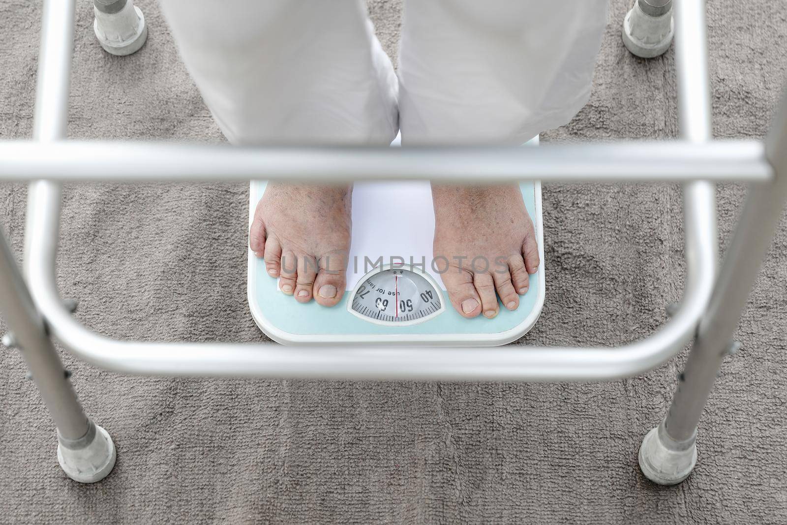 Eldely female standing on weight scale , her weight measure  54 kg.