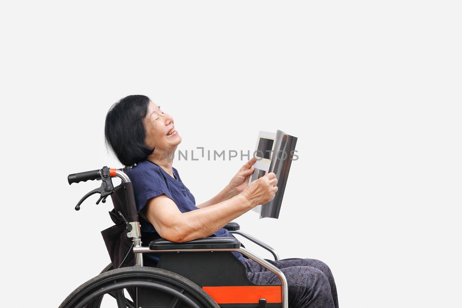Senior asian woman laughing while reading magazine on white background.
