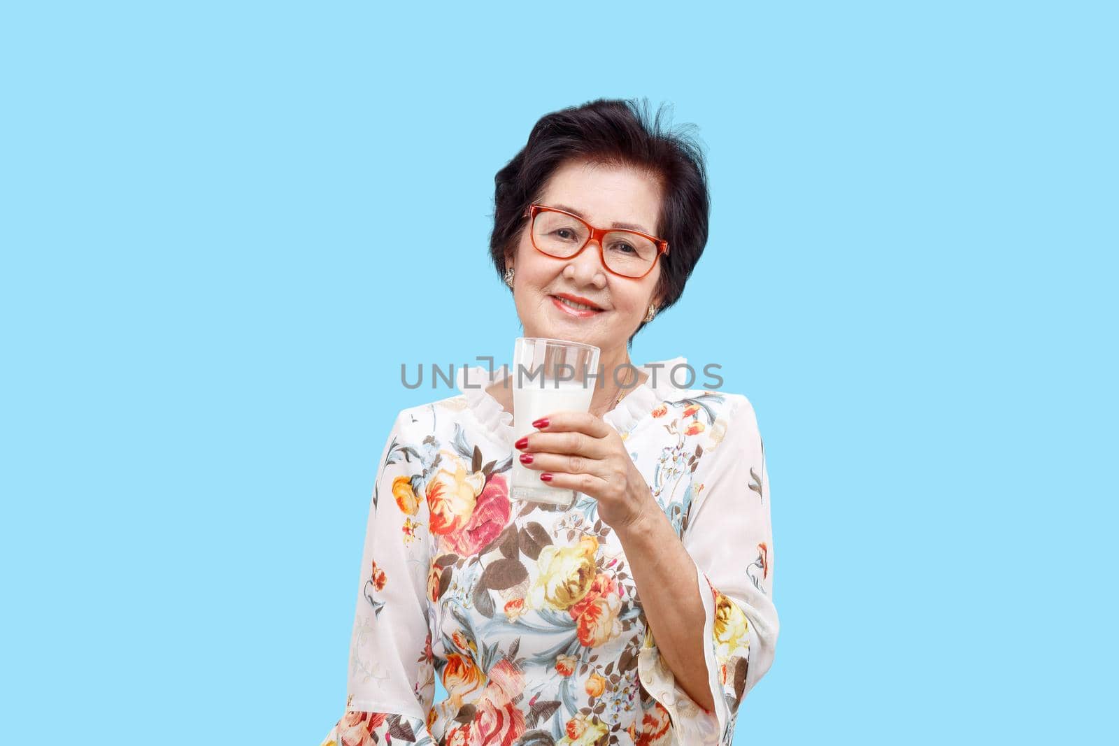 Senior woman holding a glass of milk , isolated on white background.
