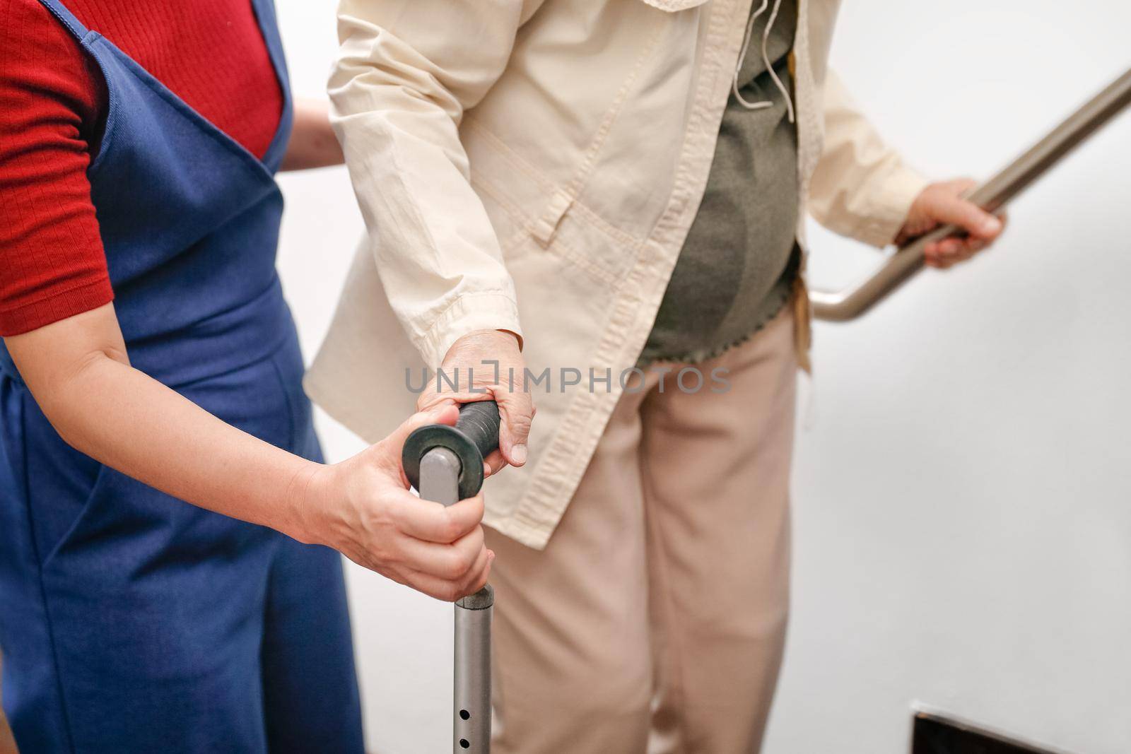 Elderly asian woman using a cane at home with daughter take care