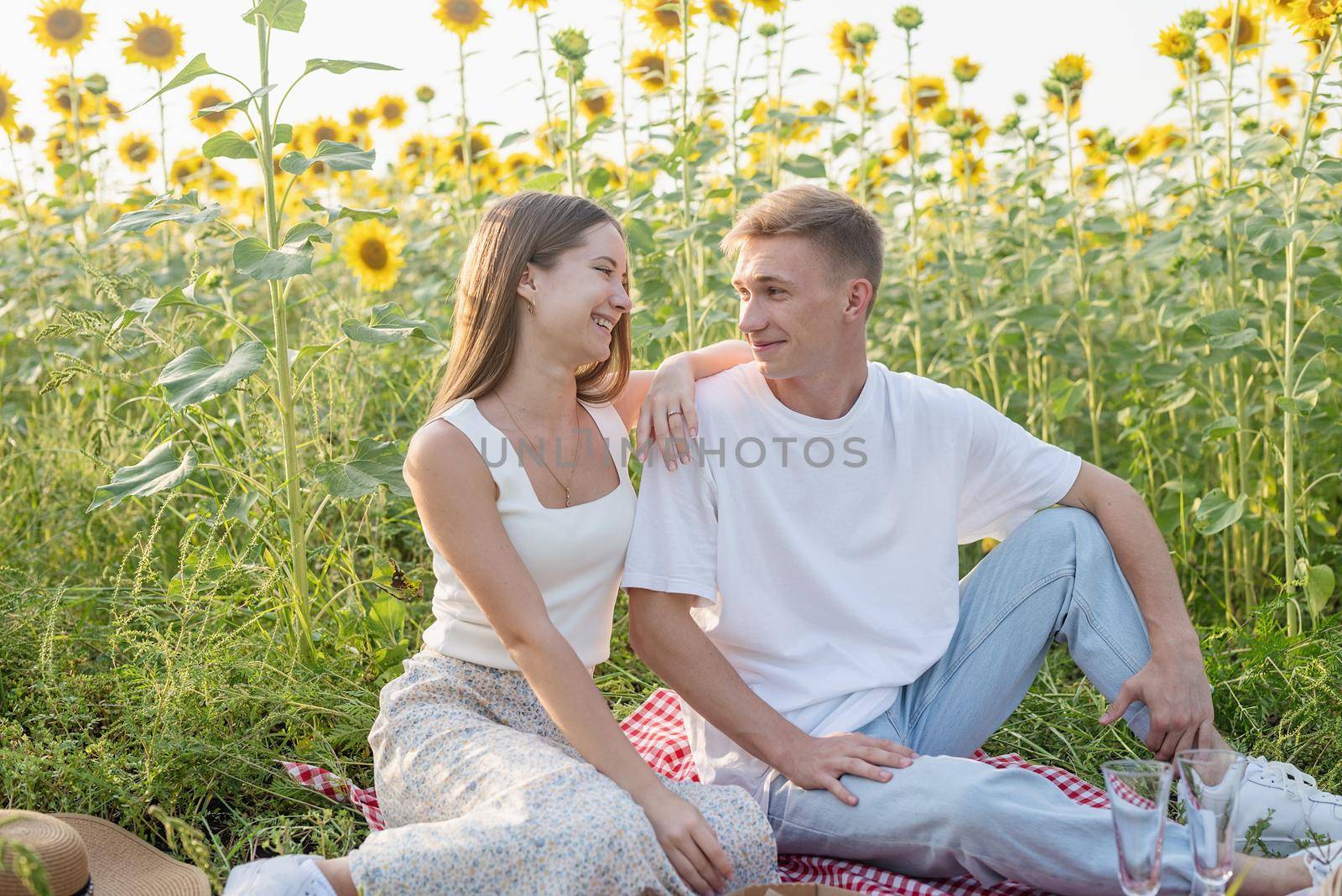 Young couple having picnic on sunflower field by Desperada