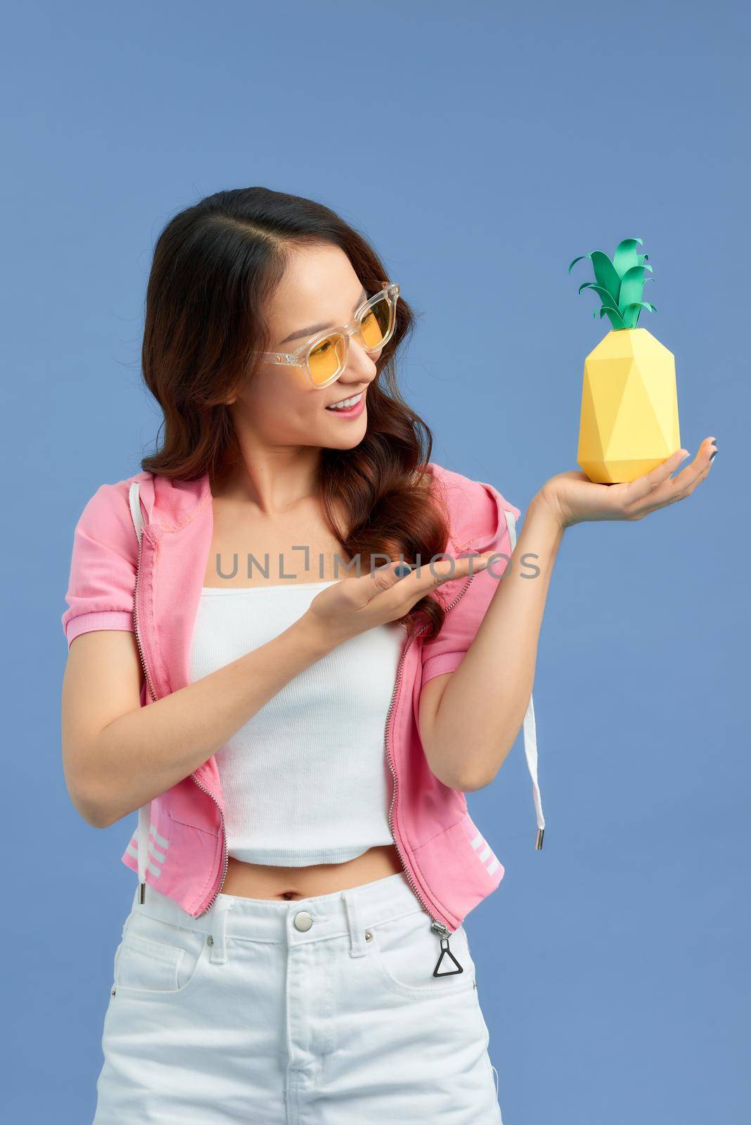 Fashion summer portrait Asian girl in sunglasses and paper pineapple over blue background