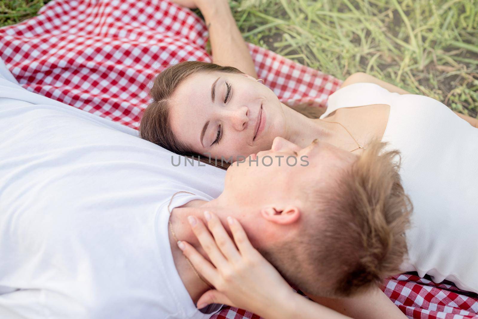 Young couple cuddling on a picnic blanket by Desperada
