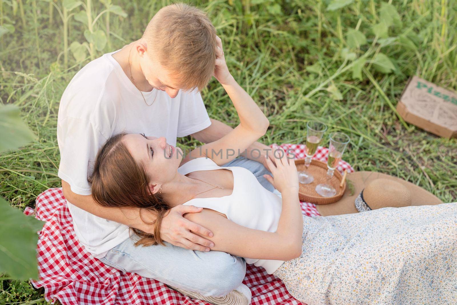 Autumn nature. Fun and liesure. Young teenage couple picnic on sunflower field in sunset, enjoying time together