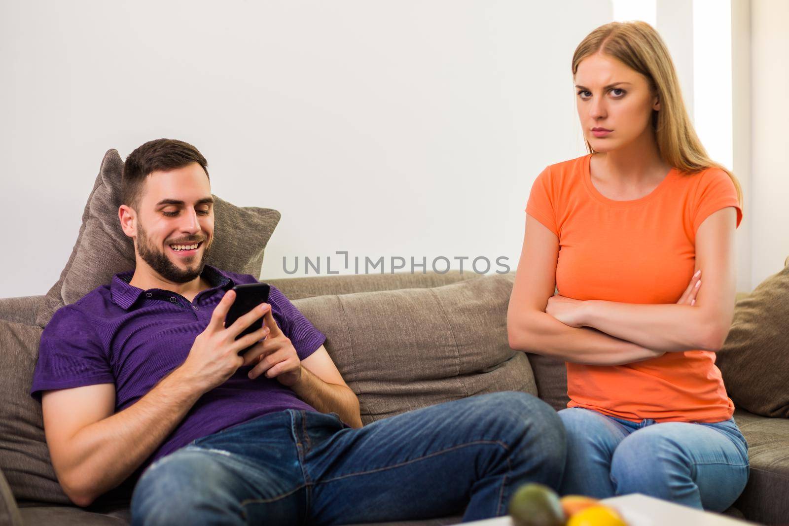 Angry wife and husband are having conflict because husband is using phone too much.