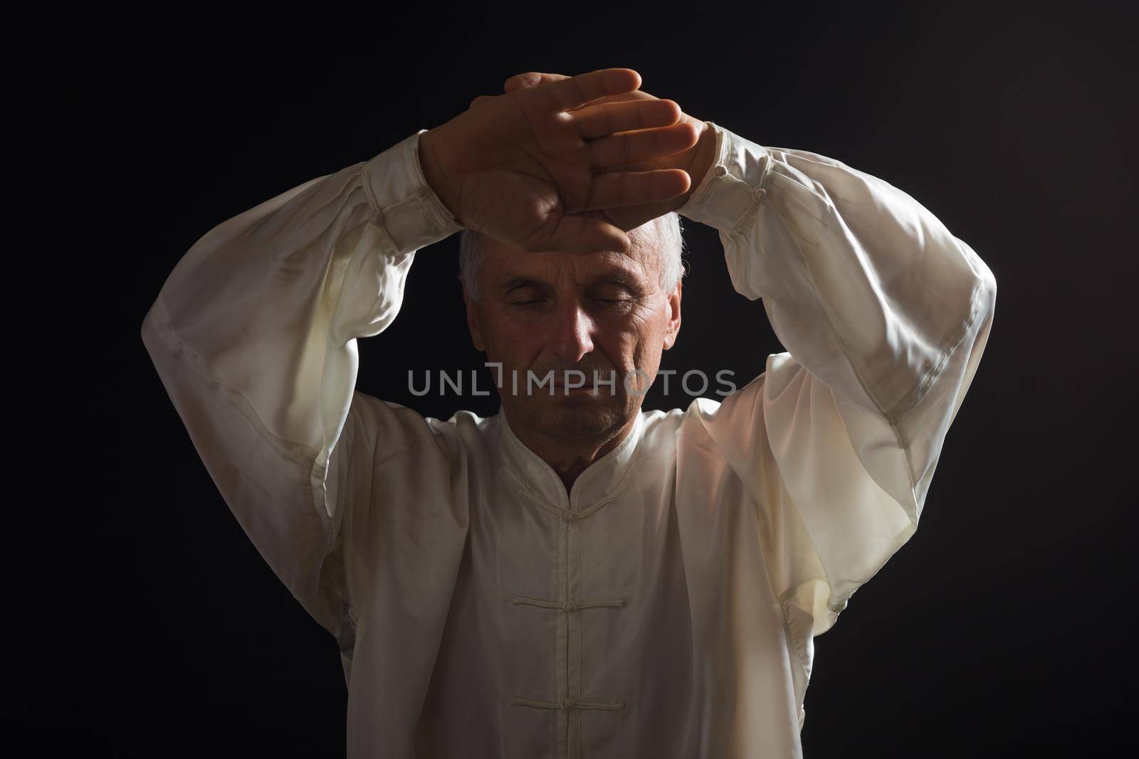 Senior man enjoys exercise Tai Chi indoor.