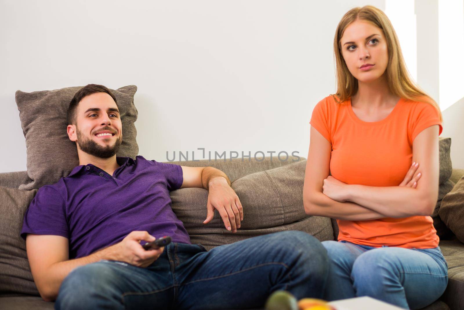 Angry wife and husband are having conflict because husband is watching tv too much.