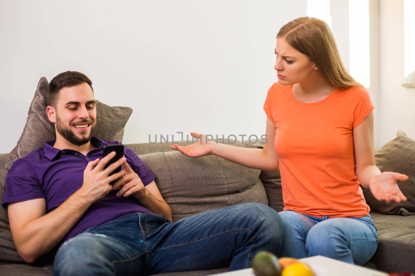 Angry wife and husband are having conflict because husband is using phone too much.