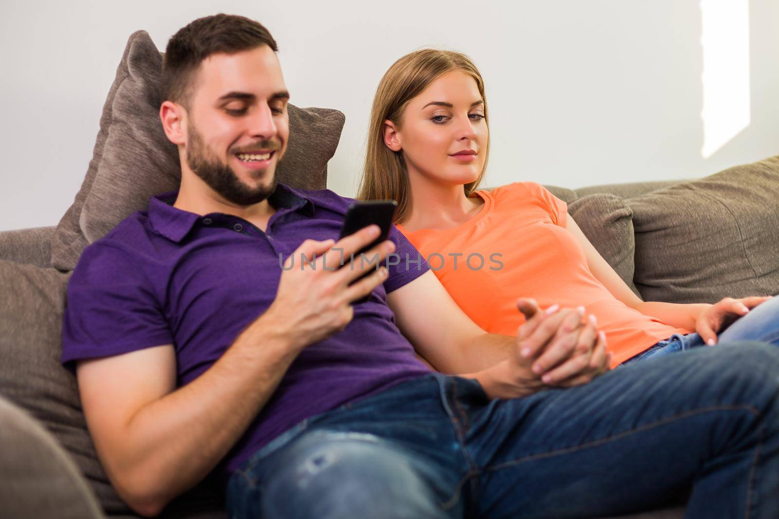 Husband using phone while his curious and jealous wife  watching what does he typing.