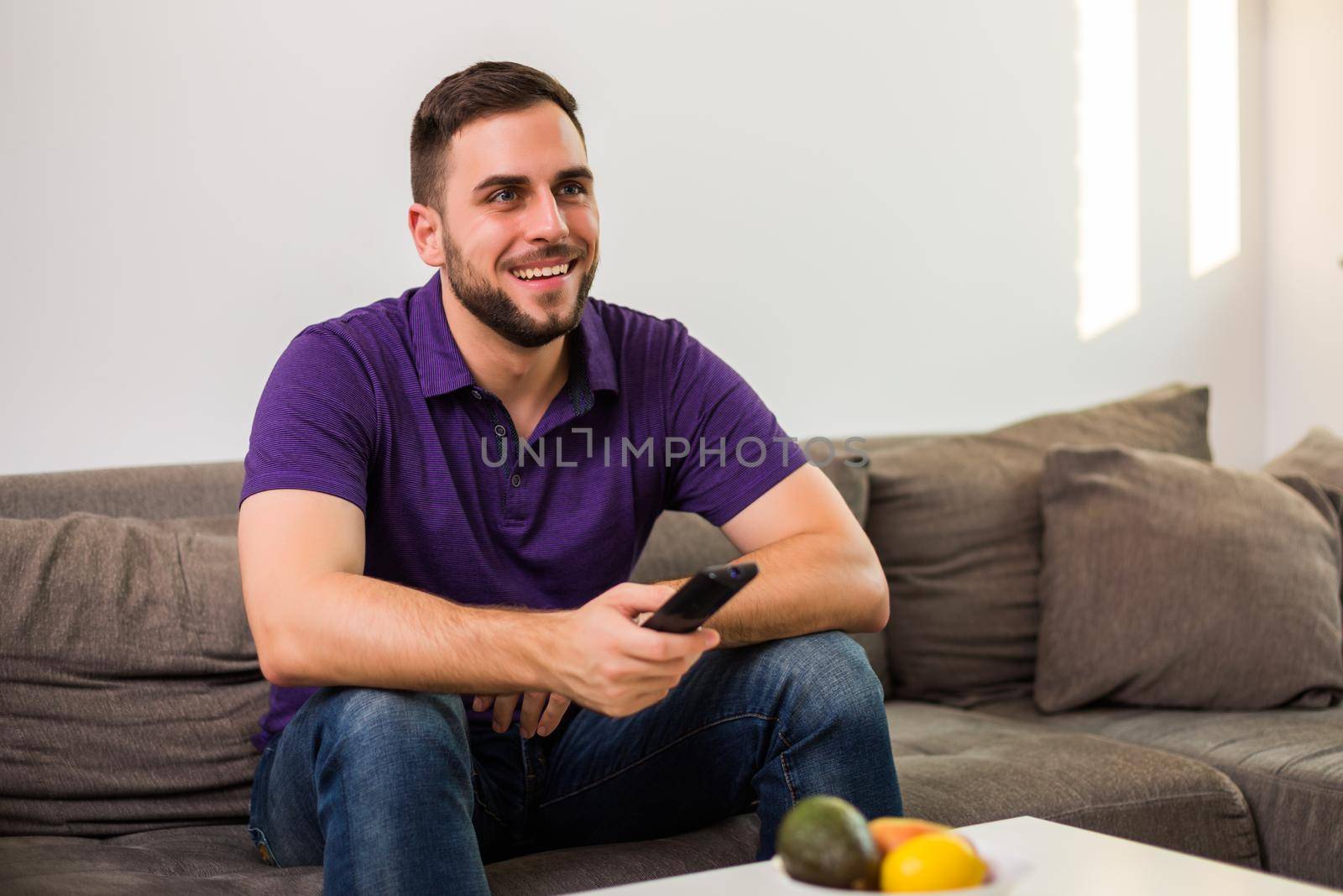 Man watching tv while sitting on sofa in his living room.
