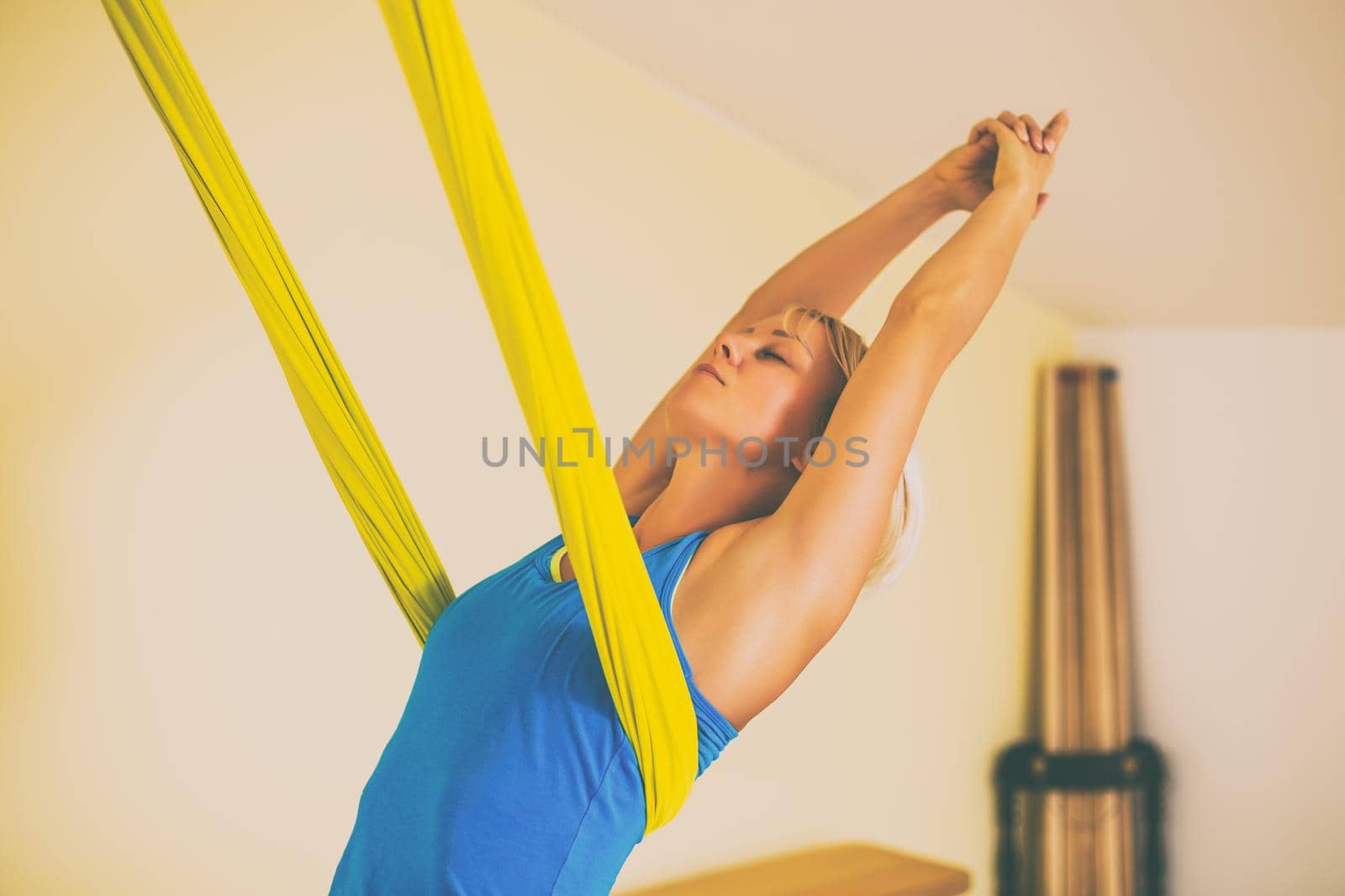 Woman doing aerial yoga in the fitness studio.Toned image.