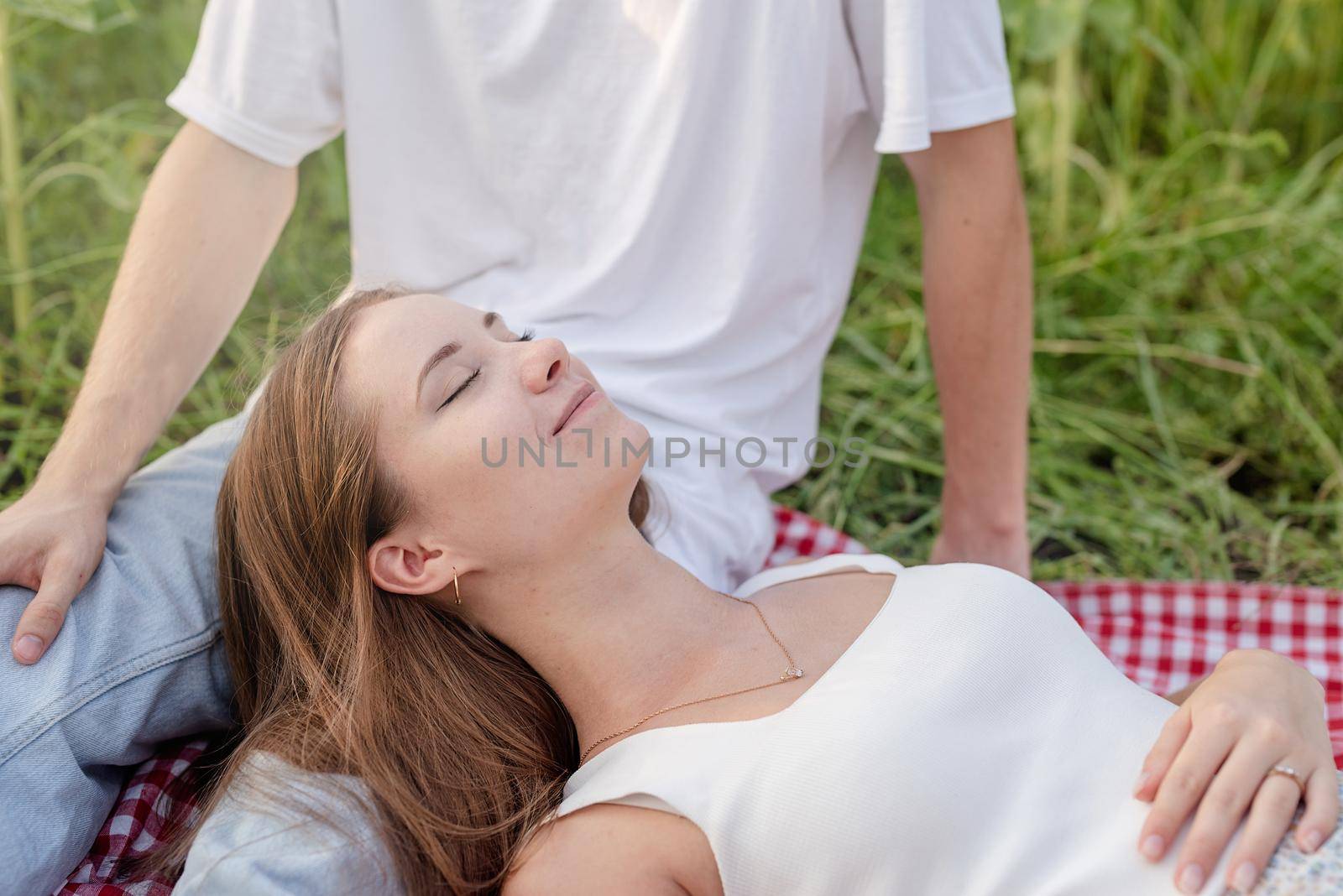 Autumn nature. Fun and liesure. Young teenage couple in white t shirts having picnic on sunflower field in sunset, enjoying time together