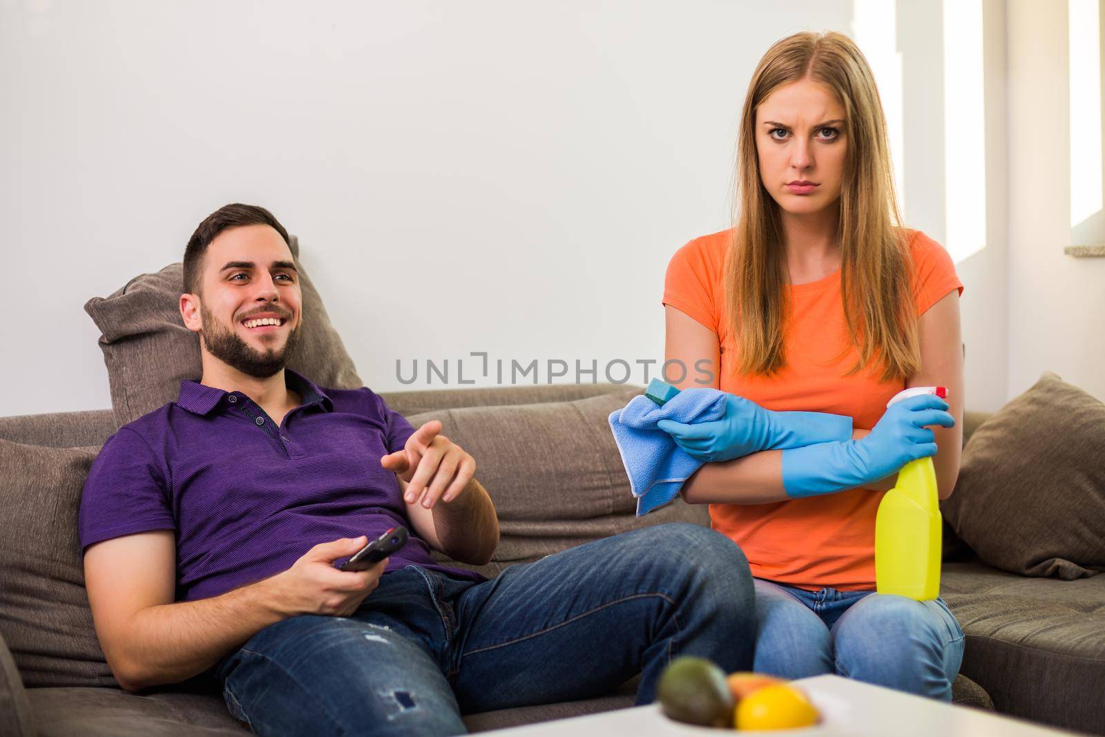 Angry wife and husband are having conflict because husband is never helping his wife with cleaning house.