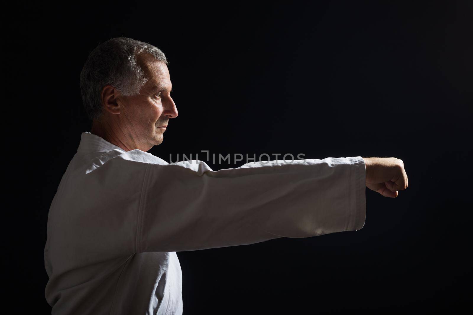 Senior man practicing karate indoor.