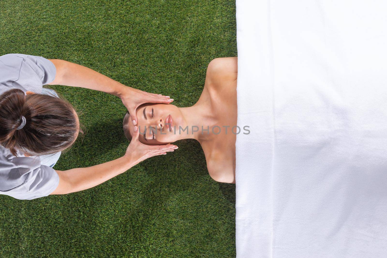 Beautiful young woman getting a face treatment at beauty spa salon on grass