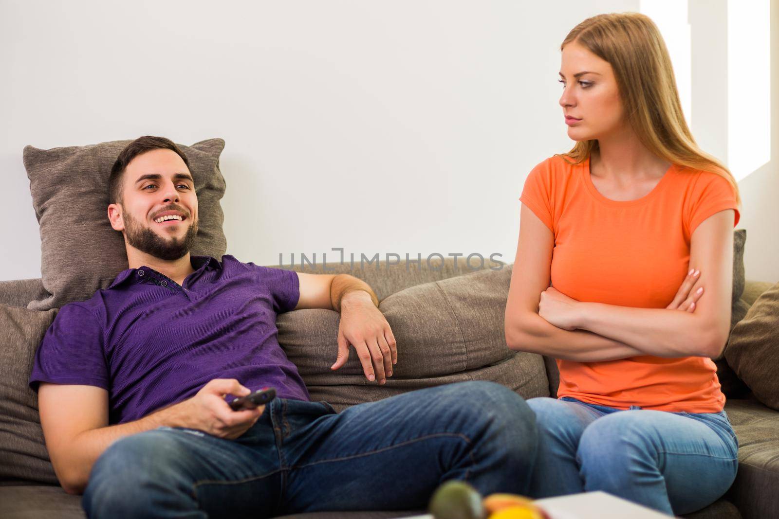 Angry wife and husband are having conflict because husband is watching tv too much.