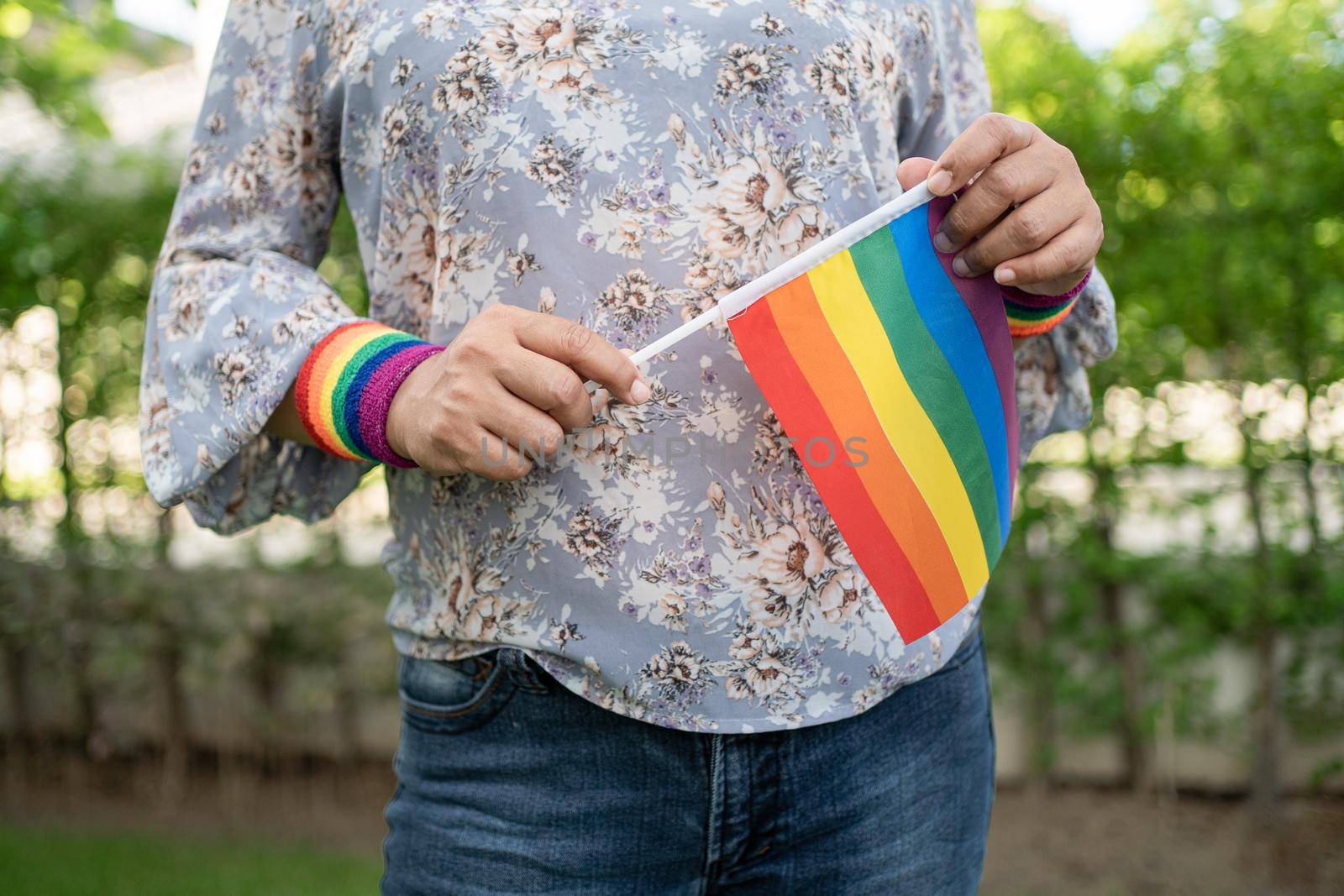 Asian lady holding rainbow color flag, symbol of LGBT pride month celebrate annual in June social of gay, lesbian, bisexual, transgender, human rights.