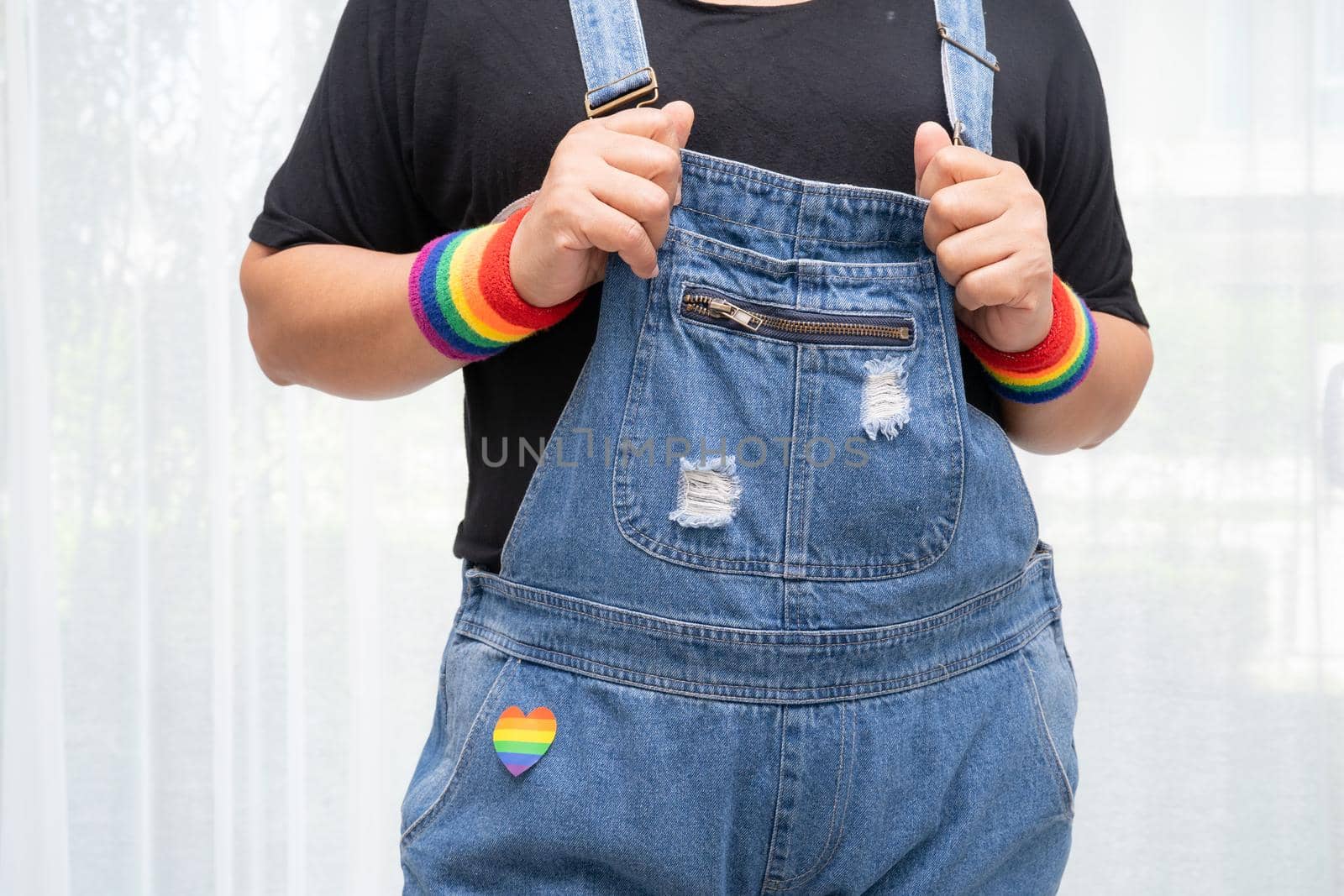 Asian lady wearing rainbow flag wristbands, symbol of LGBT pride month celebrate annual in June social of gay, lesbian, bisexual, transgender, human rights.