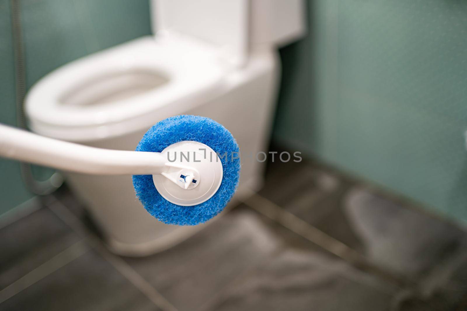 Maid cleaning toilet bowl with brush in bathroom at home. by pamai