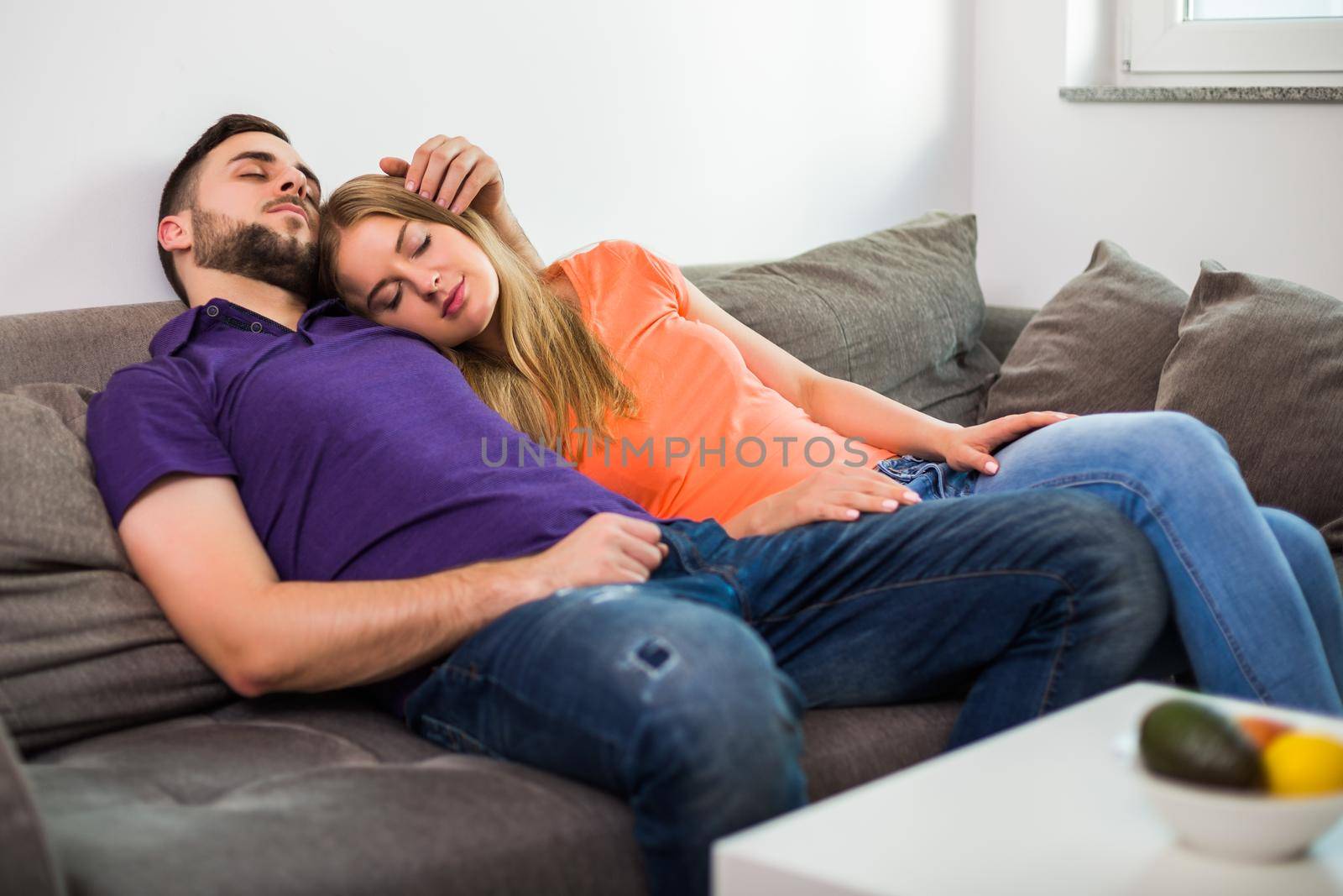 Couple enjoys napping together on sofa while they spending time together at their home.