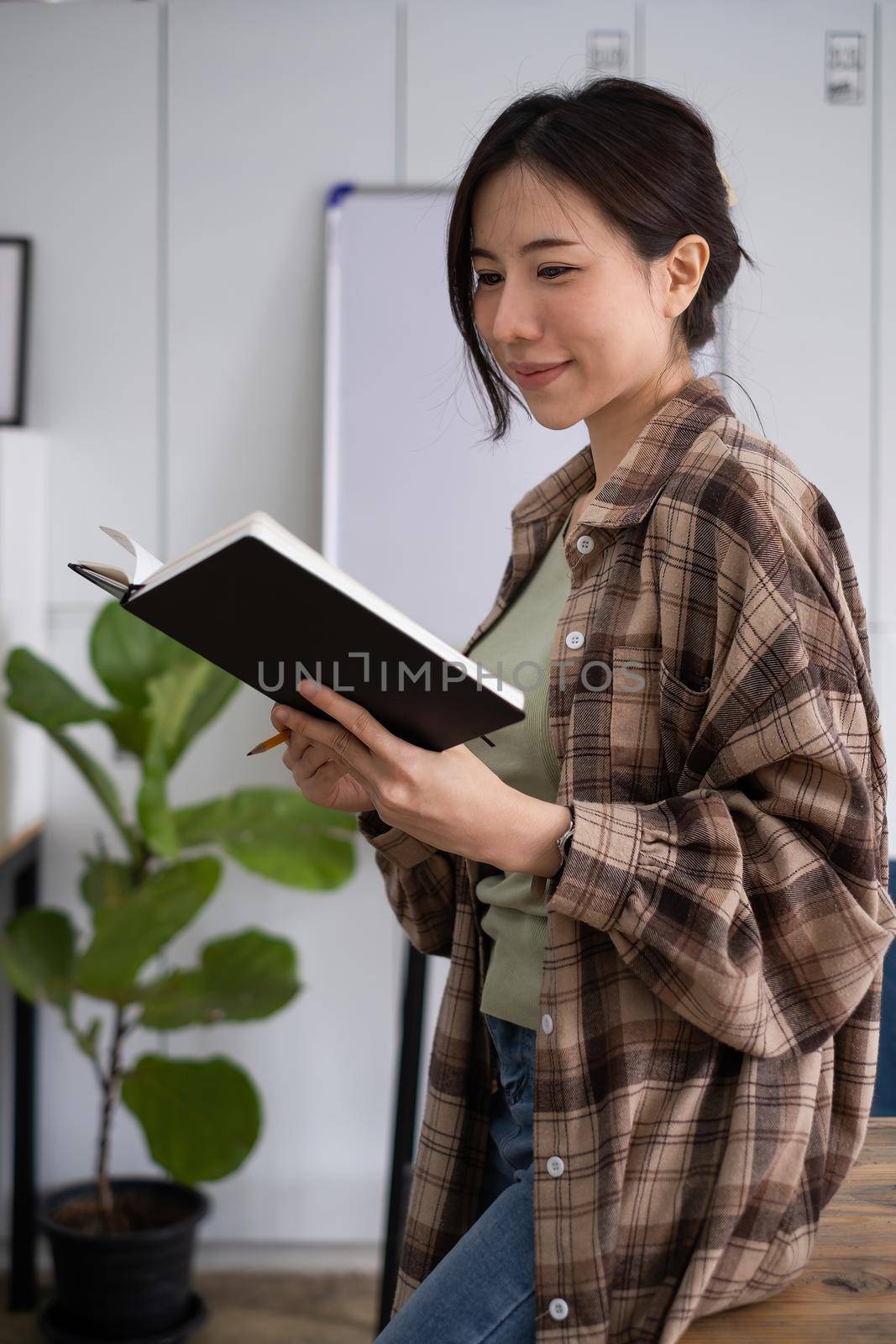 Portrait of cheerful asian woman with casual life on desk in home office. Concept of young business people working at home by itchaznong