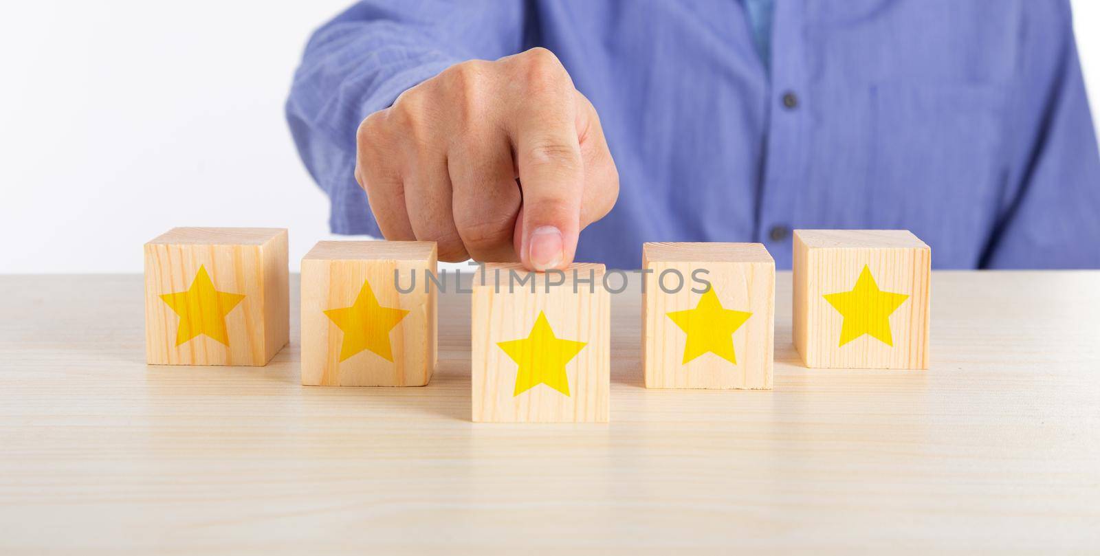 Hand touching wooden cube with five star shape on desk by tehcheesiong