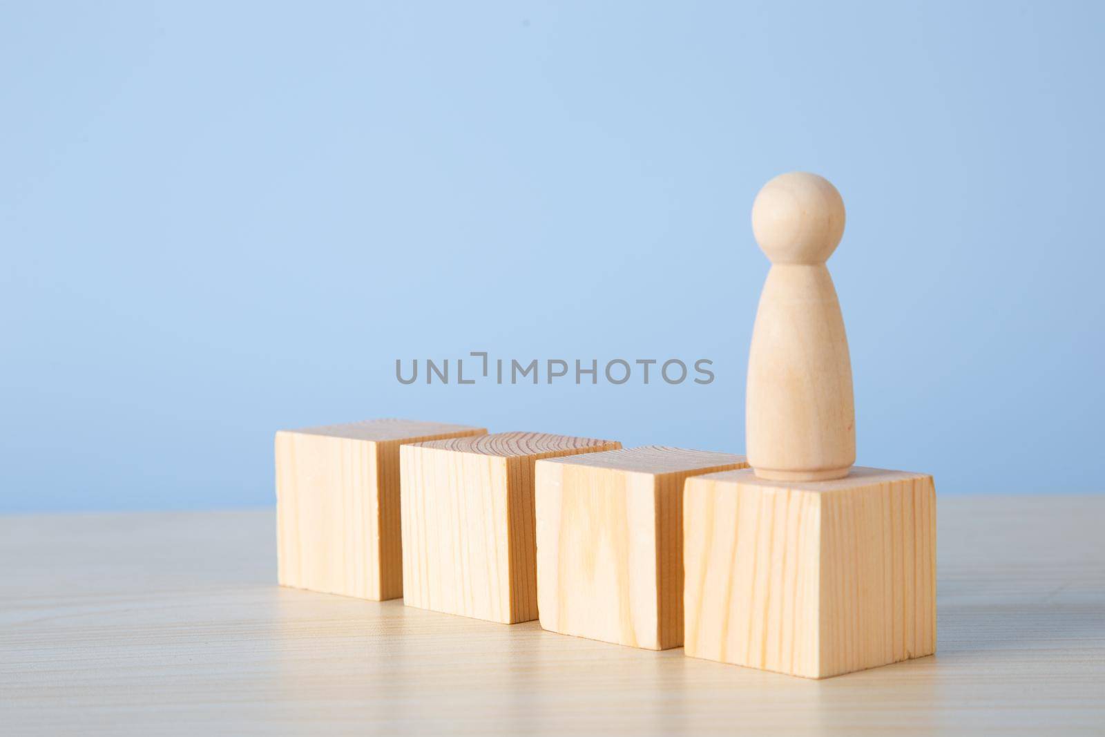 Career growth, development. Leadership, goal achievement. Wooden people figures on top of wooden blocks