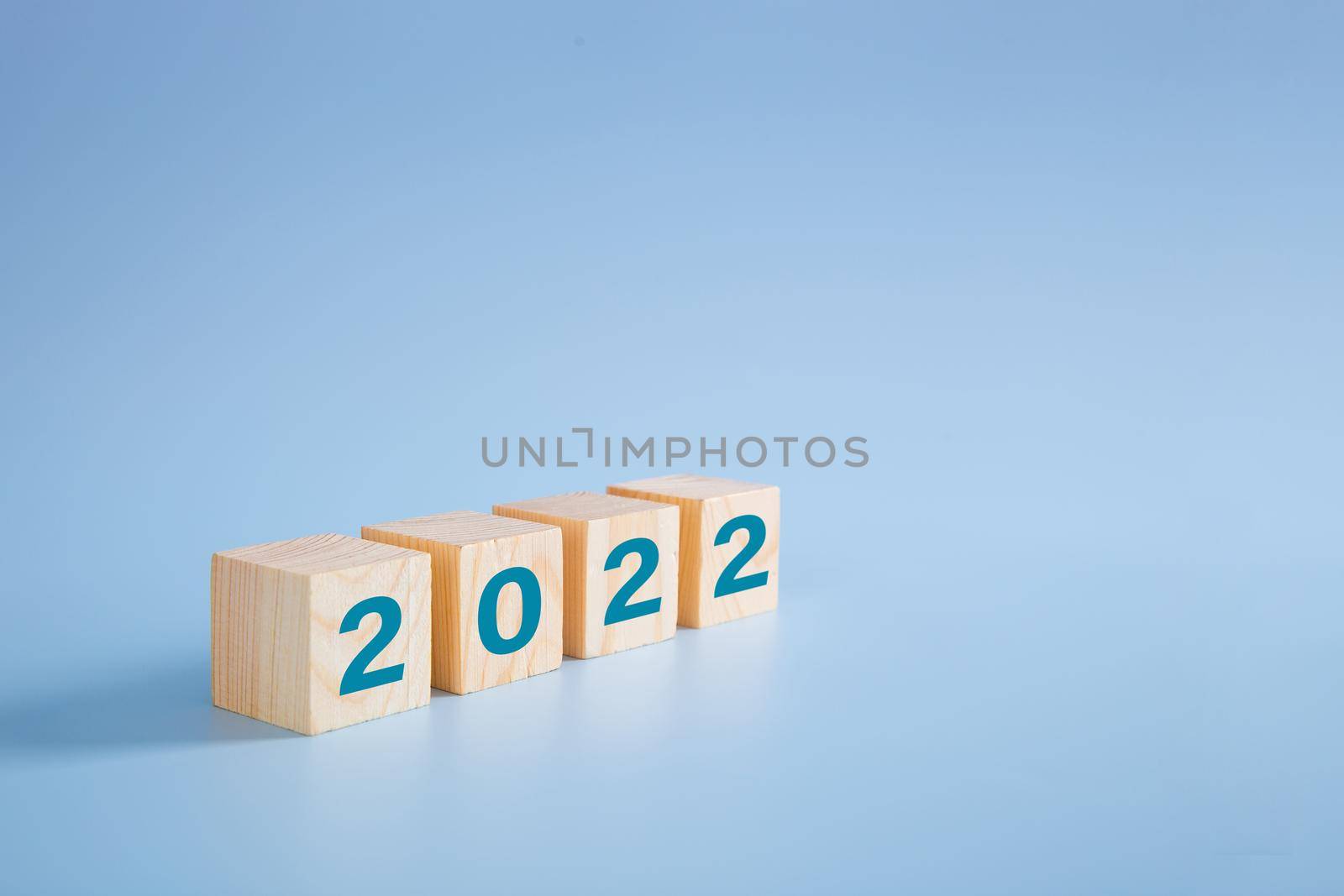 2022 number on wooden block on blue background  by tehcheesiong